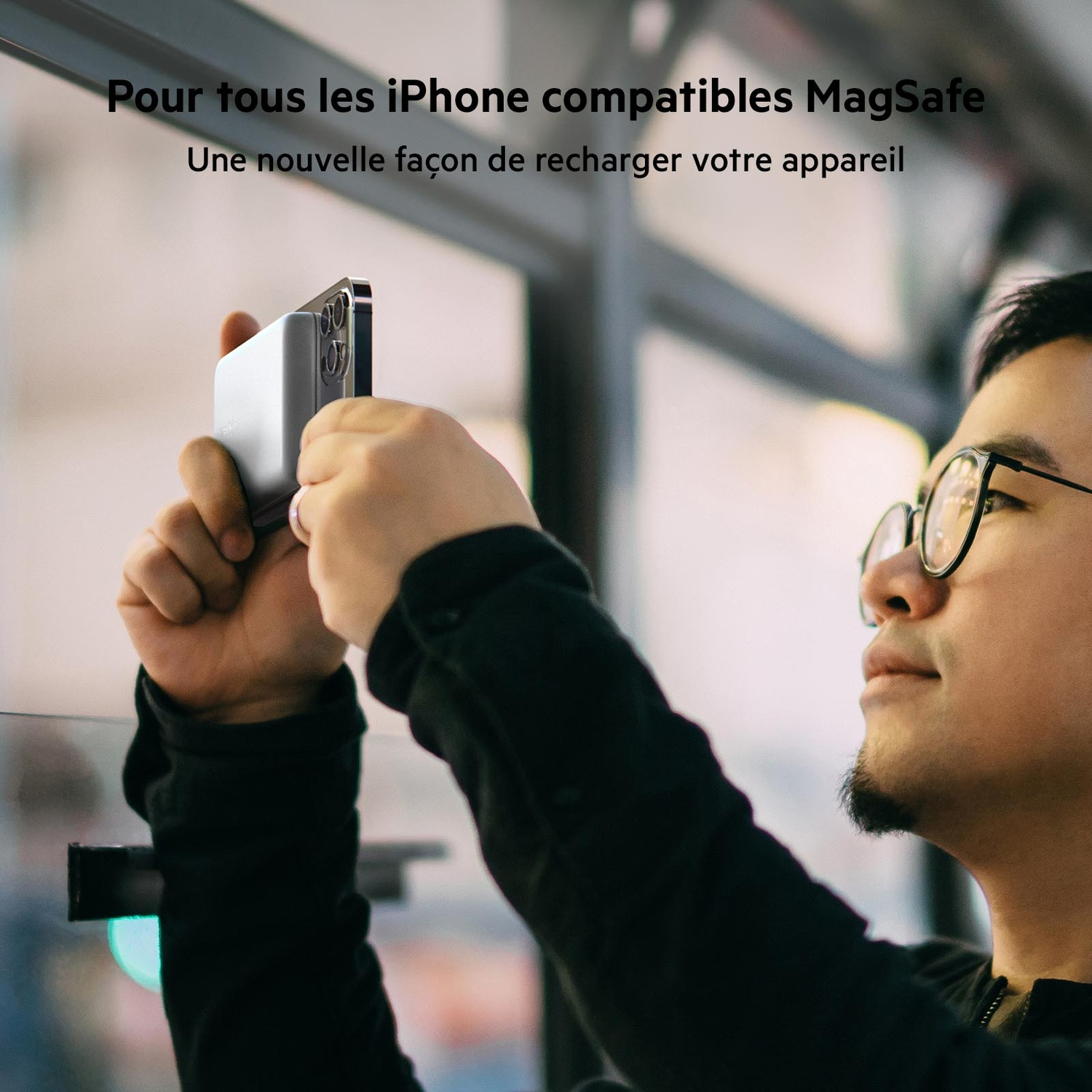 Homme tenant un téléphone près d'un socle de chargement. Le téléphone est connecté. Texte en haut.