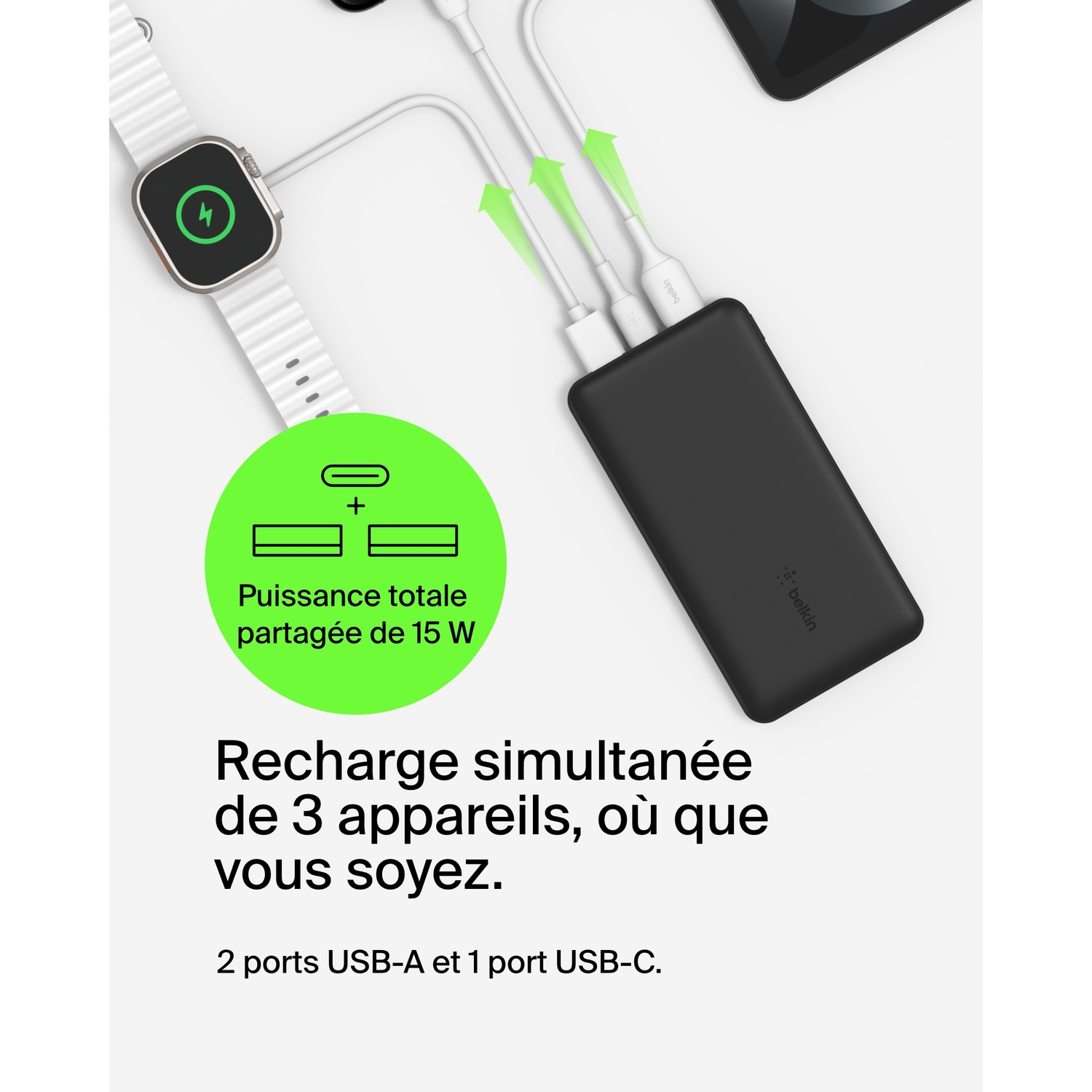Une batterie externe noire chargeant une montre, un téléphone et une tablette.