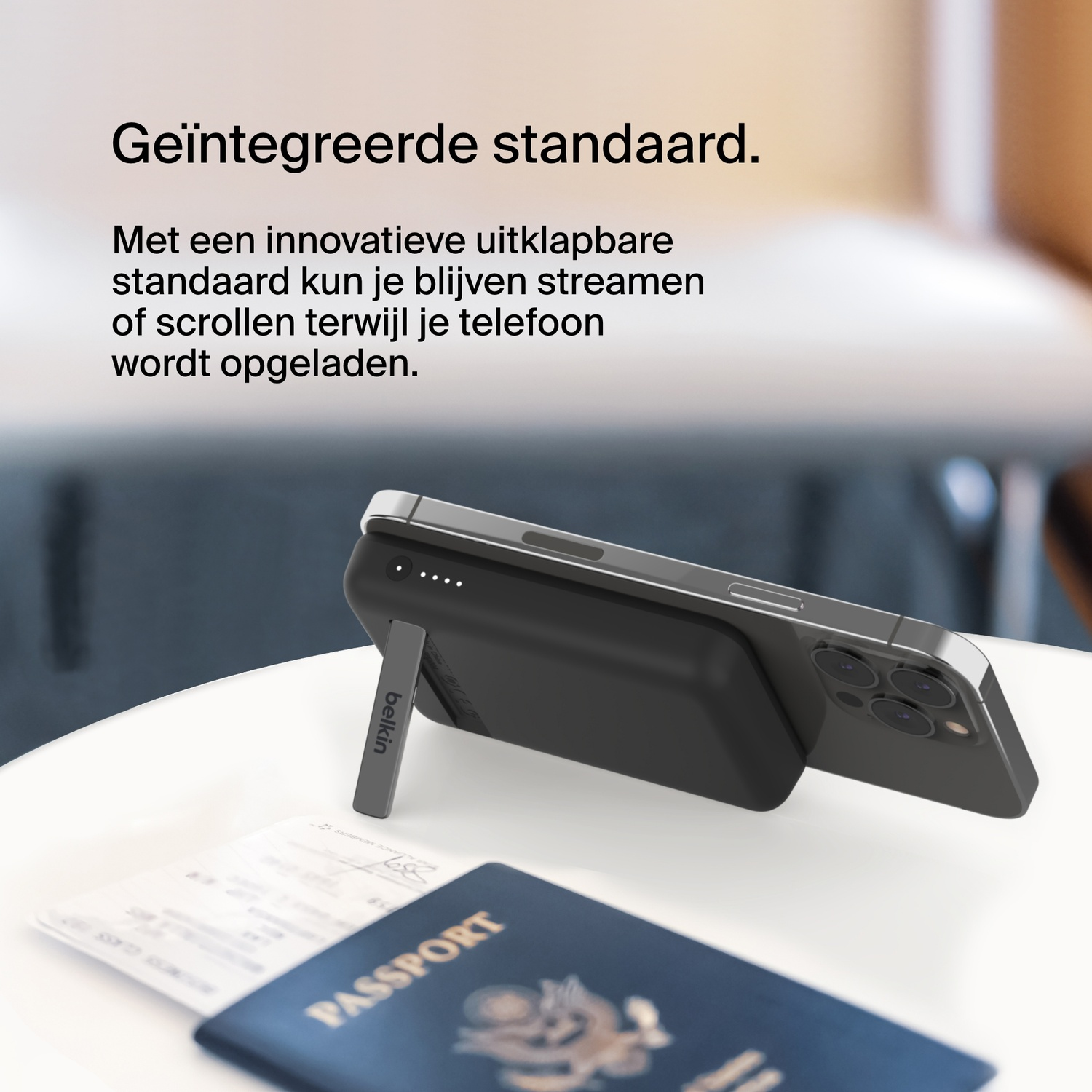 Een telefoon die oplaadt op een powerbank met een standaard. Paspoort en tickets op een tafel.
