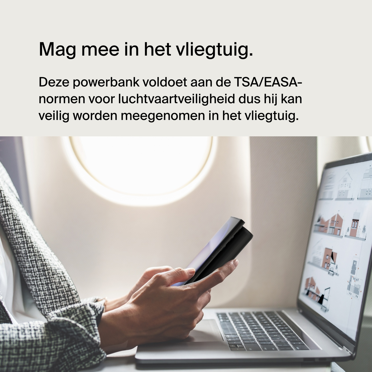Hands holding a tablet and a phone connected to a power bank, inside an airplane cabin.
