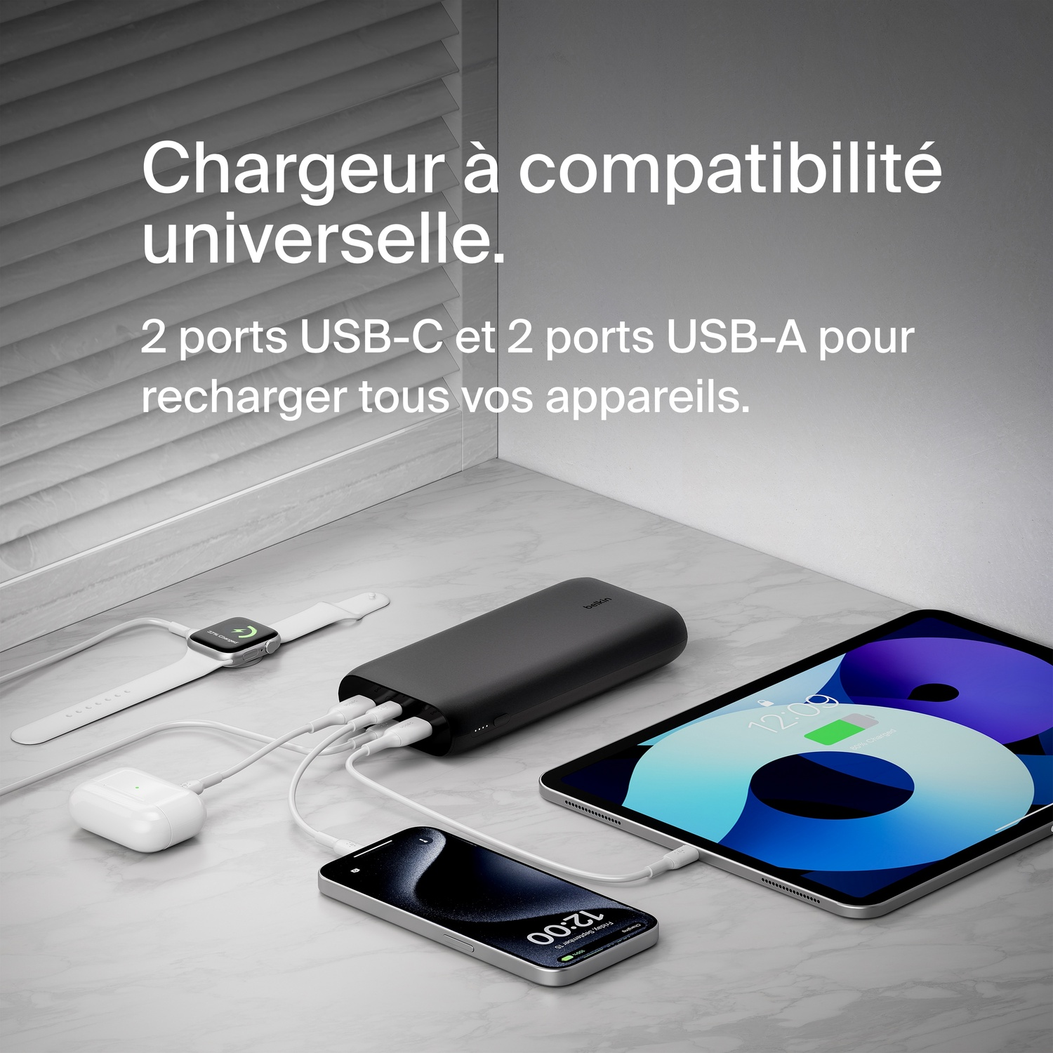 Une station de charge noire avec plusieurs appareils, dont une Apple Watch, des AirPods et un téléphone.