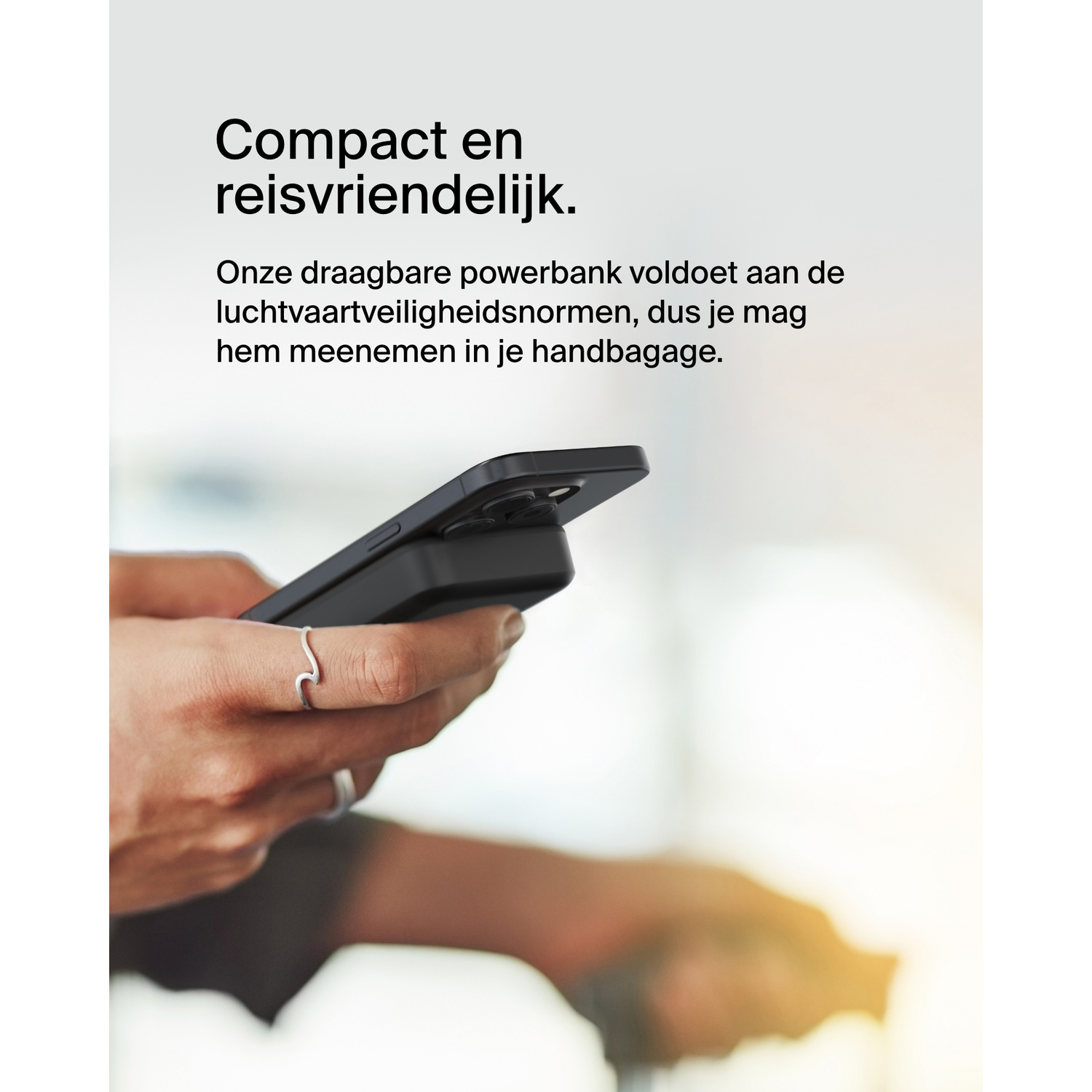 Een hand die een telefoon met een powerbank vasthoudt, getoond in een reiscontext.