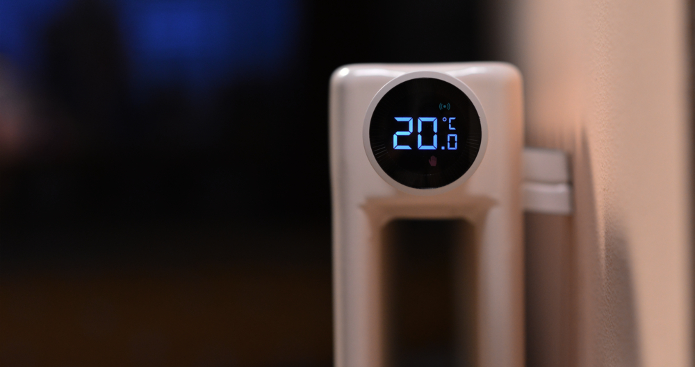 Zbliżenie białego inteligentnego termostatu wyświetlającego 20°C na ekranie cyfrowym.