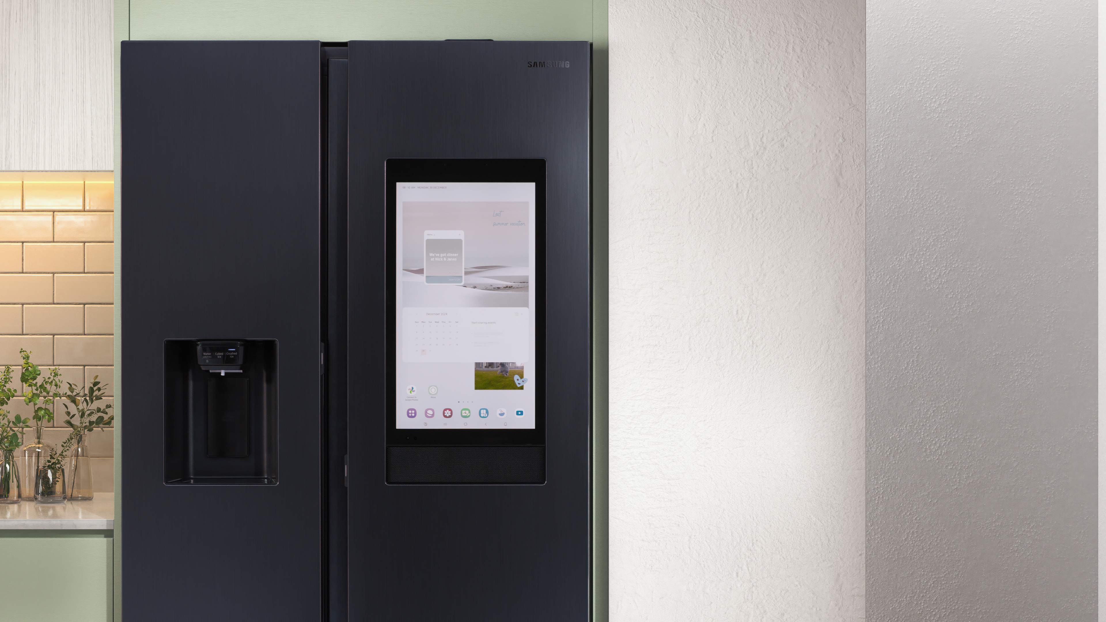 Schwarzer Kühlschrank mit Touchscreen-Display, das eine Benutzeroberfläche zeigt, und hellgrüner Wand.