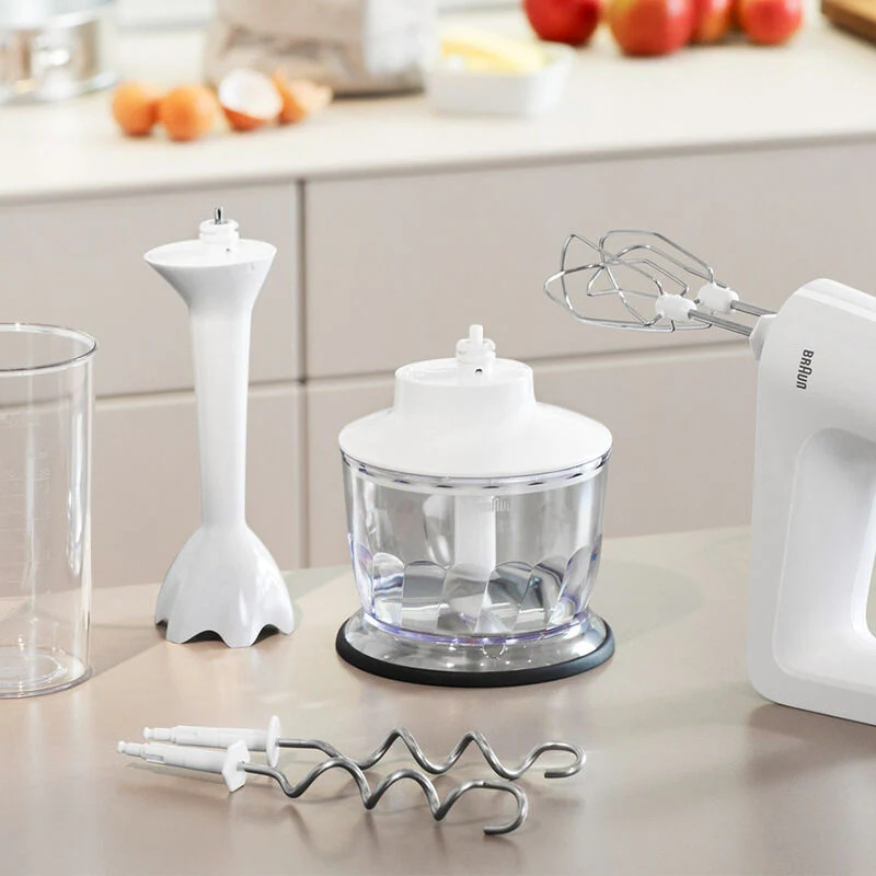 Na blacie ustawiono różne białe akcesoria do urządzeń kuchennych Braun. Jest blender i mikser.