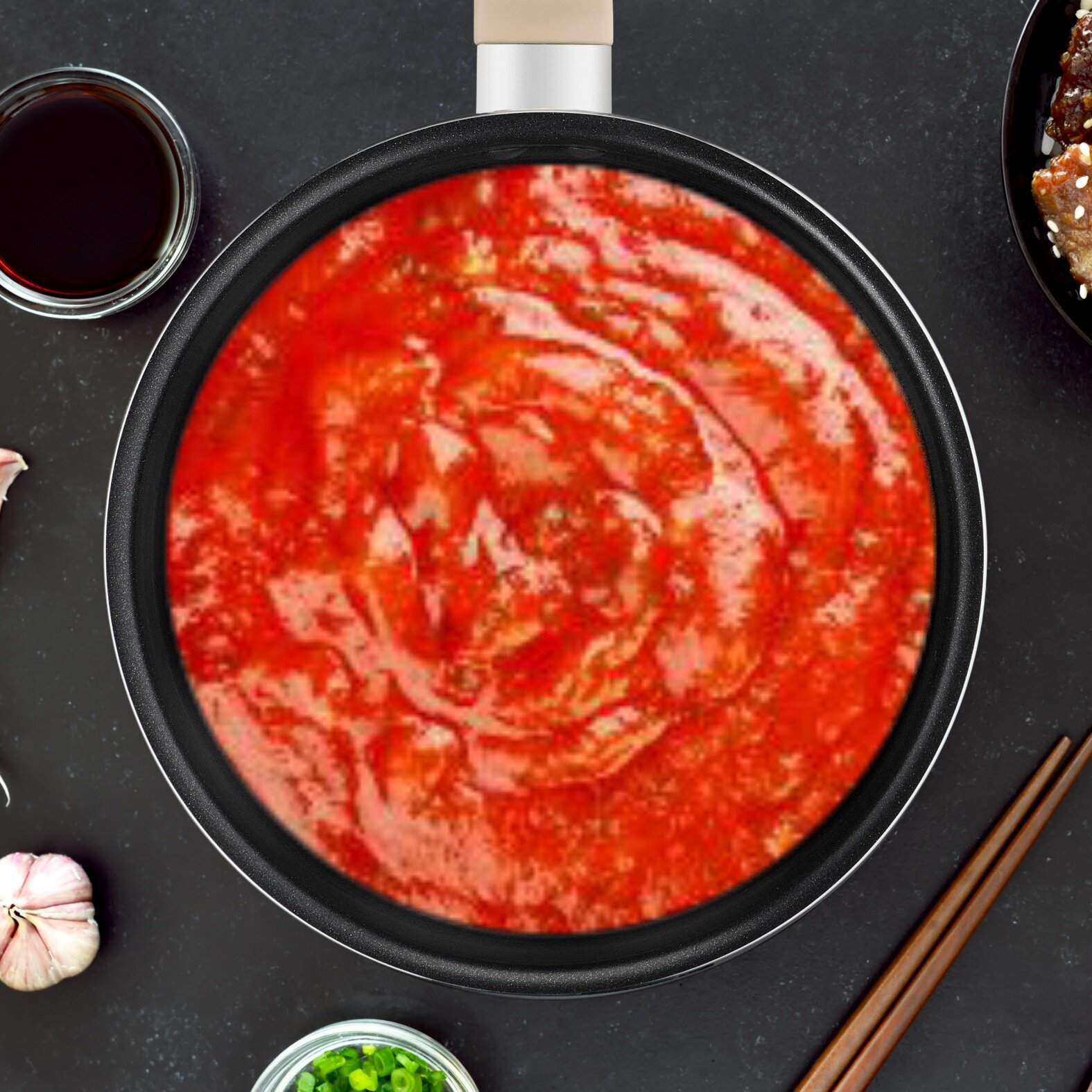 Patelnia z czerwonym sosem, otoczona składnikami i pałeczkami.