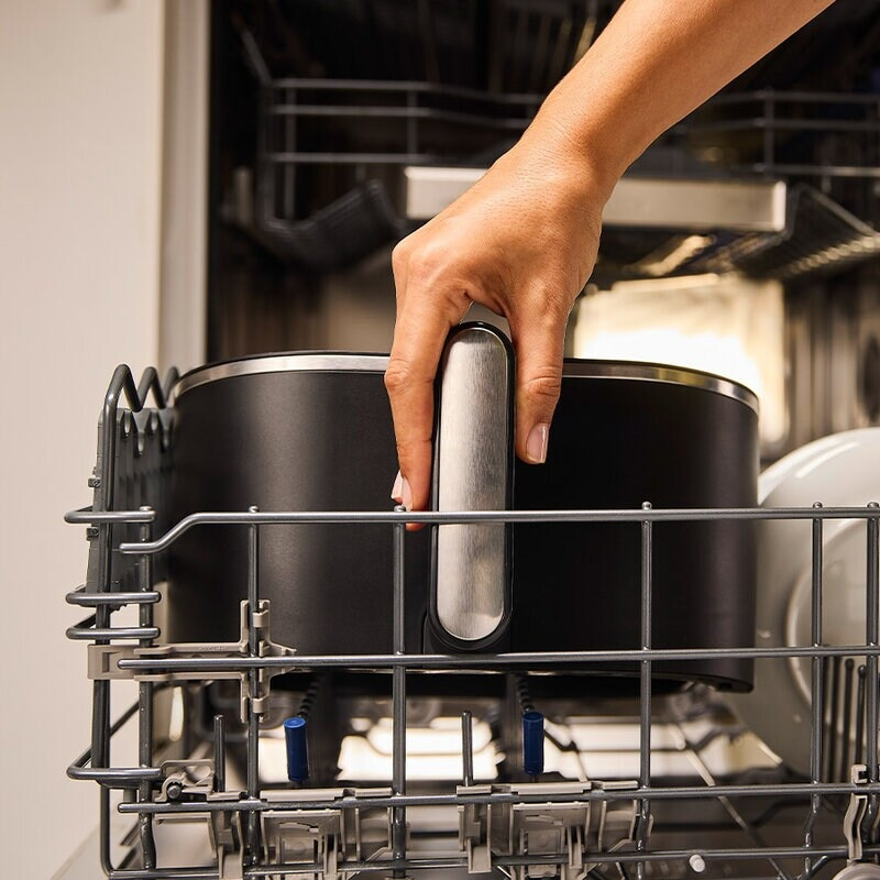 Ręka trzymająca garnek w zmywarce.