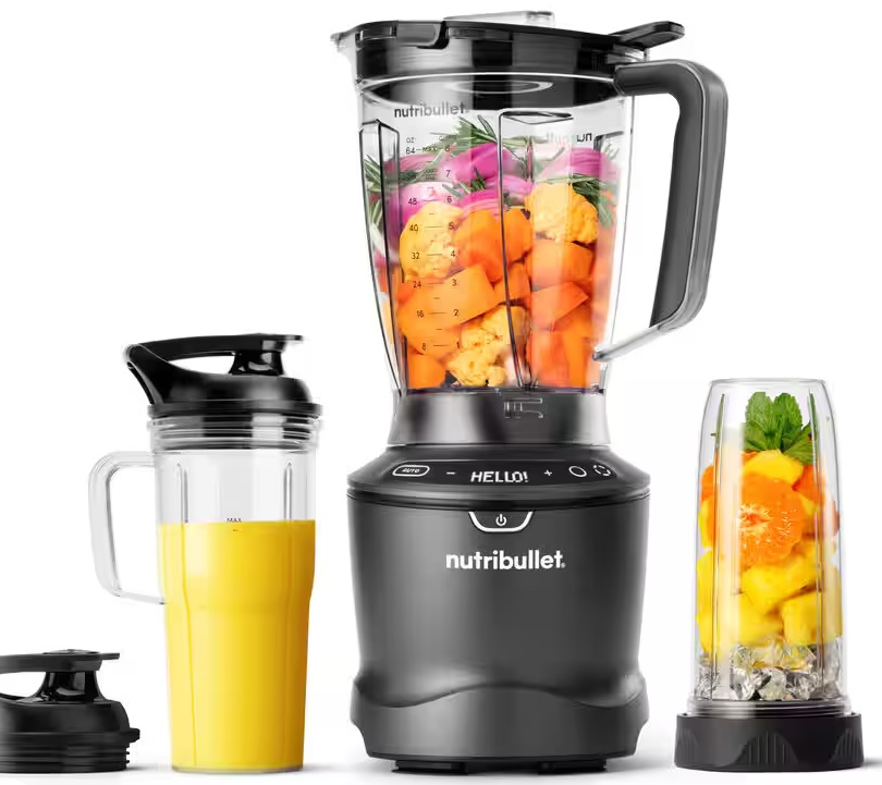 Czarny blender ze składnikami w środku. Żółte smoothie jest w kubku po lewej stronie. Dwa dodatkowe kubki.