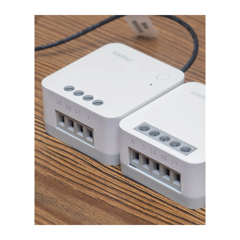 Dwa małe białe przekaźniki elektryczne na drewnianej powierzchni.