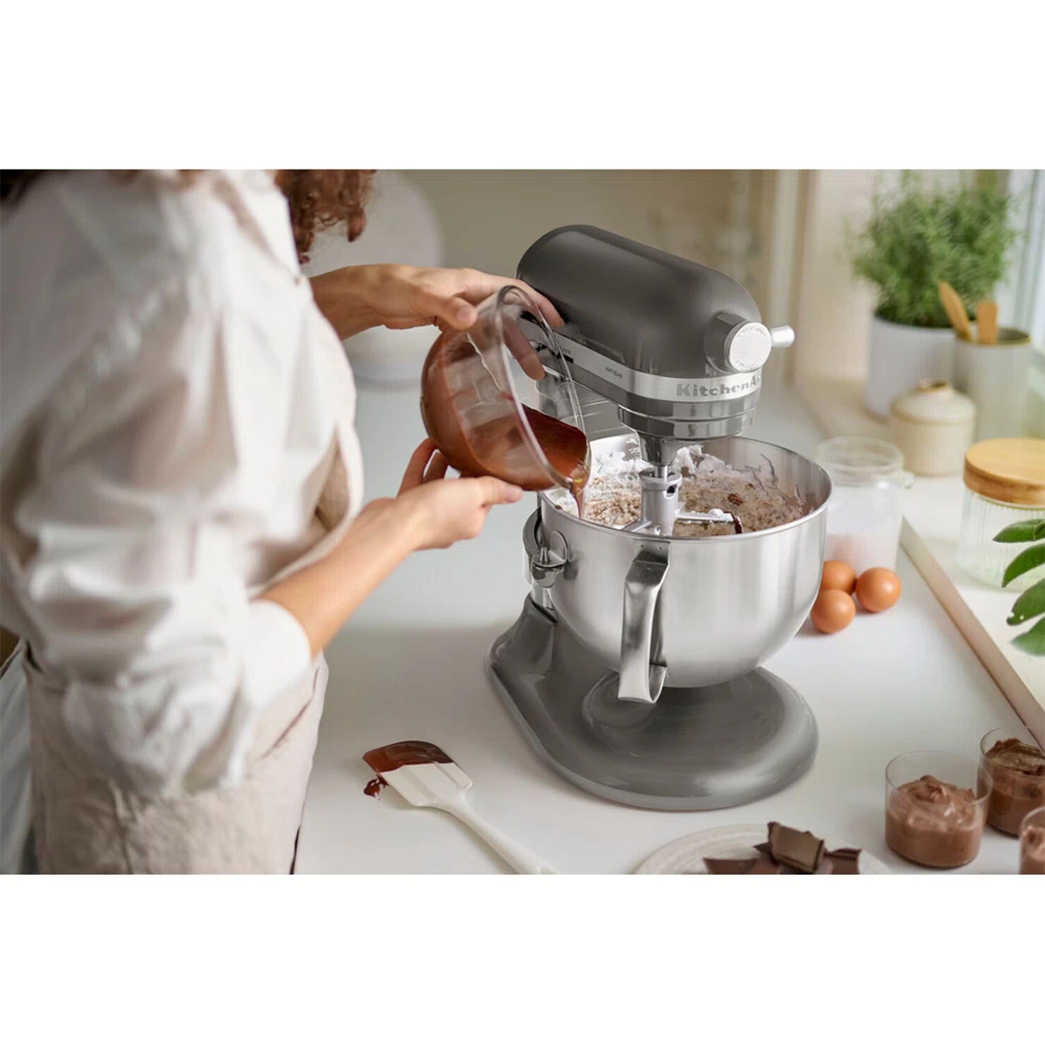 Una persona versa cioccolato in un mixer a colonna con farina e uova.