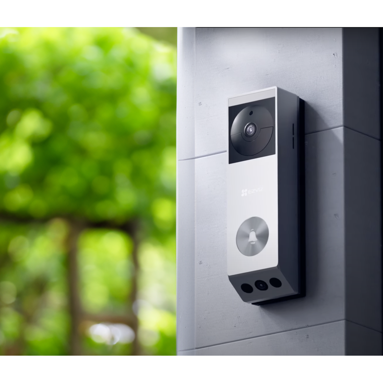 White and silver doorbell mounted on a wall. It has a camera, a button, and a speaker.