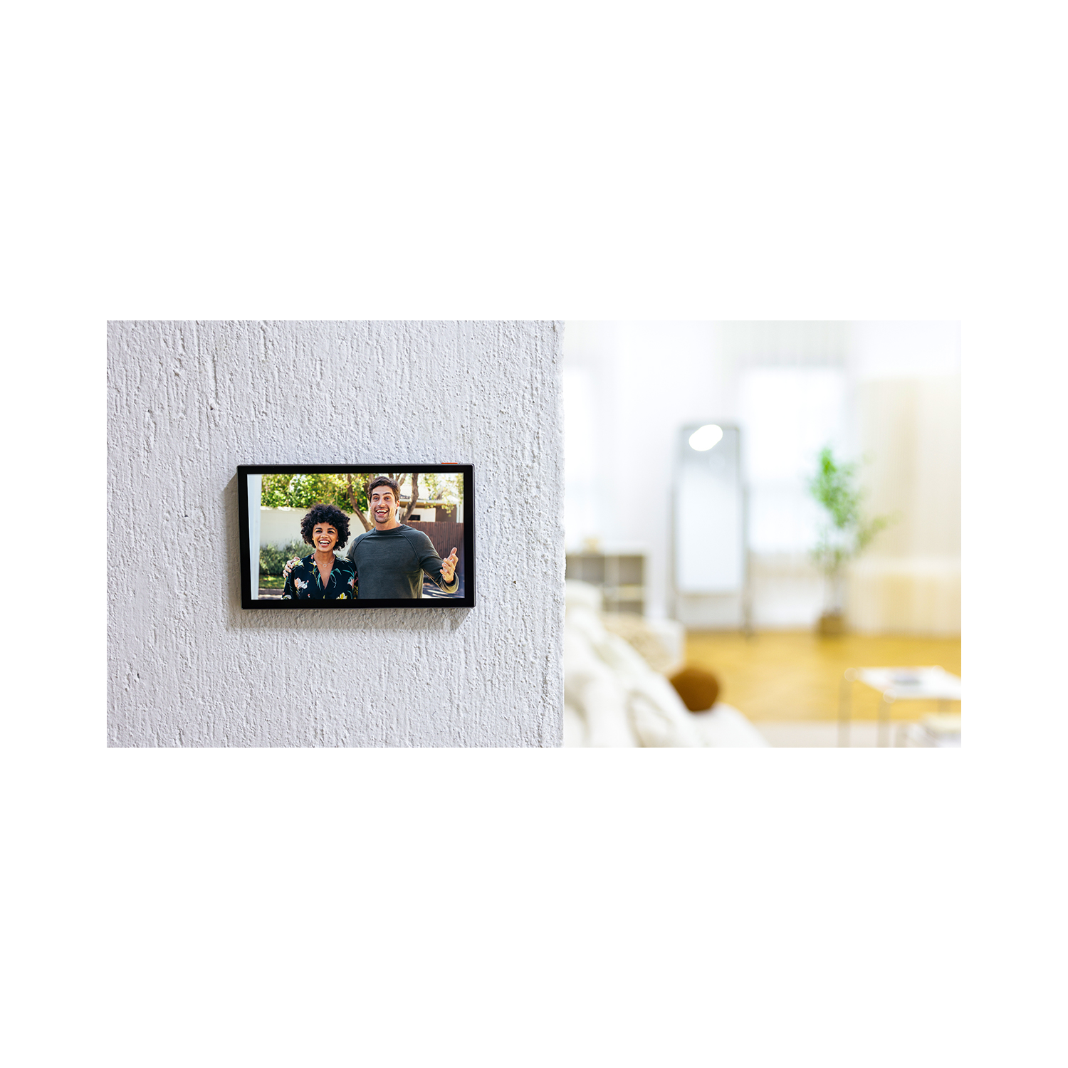 A smart home panel on a white wall, displaying two people on a video call.