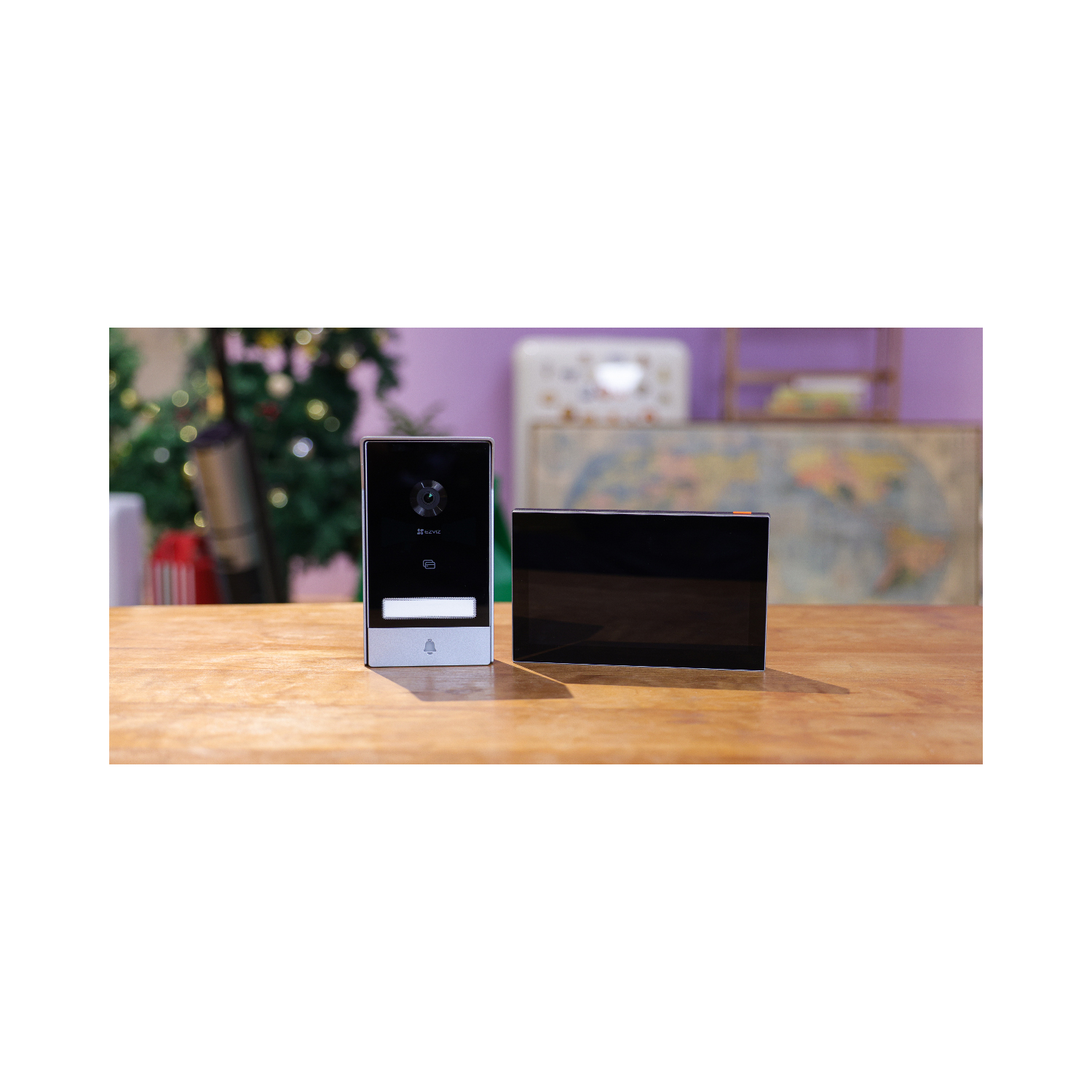 A smart doorbell system with a screen and a doorbell button on a table.