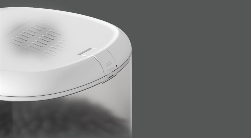 Zbliżenie białej pokrywy pojemnika z wgnieceniem i napisem 'PRESS'.