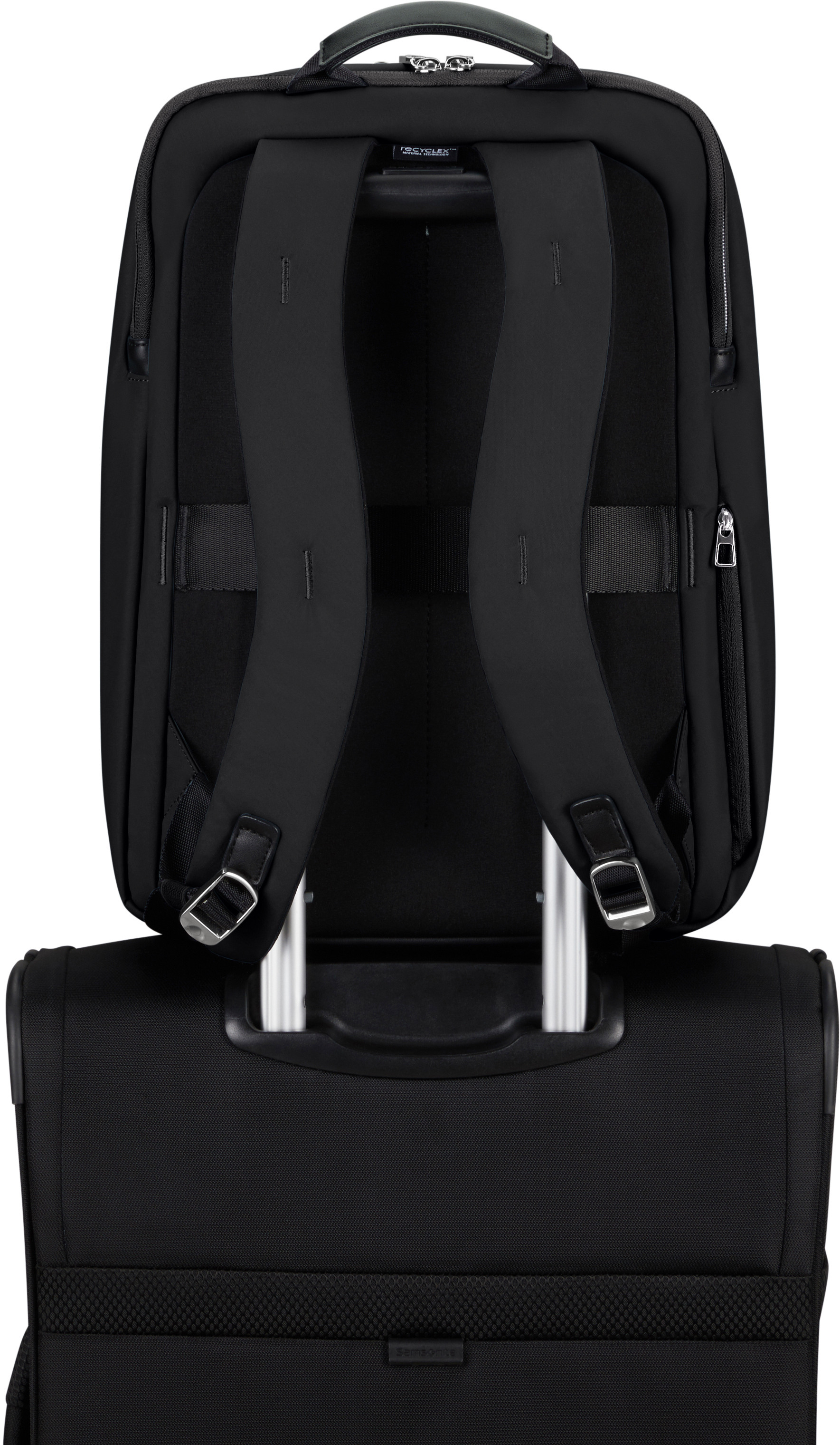 Schwarzer Rucksack auf einem schwarzen Koffer mit silbernen Griffen und Gurten.
