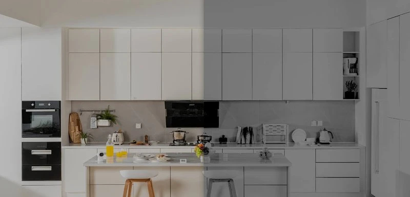 Kuchnia z białymi szafkami, sprzętami i wyspą, z jasną i ciemną stroną.