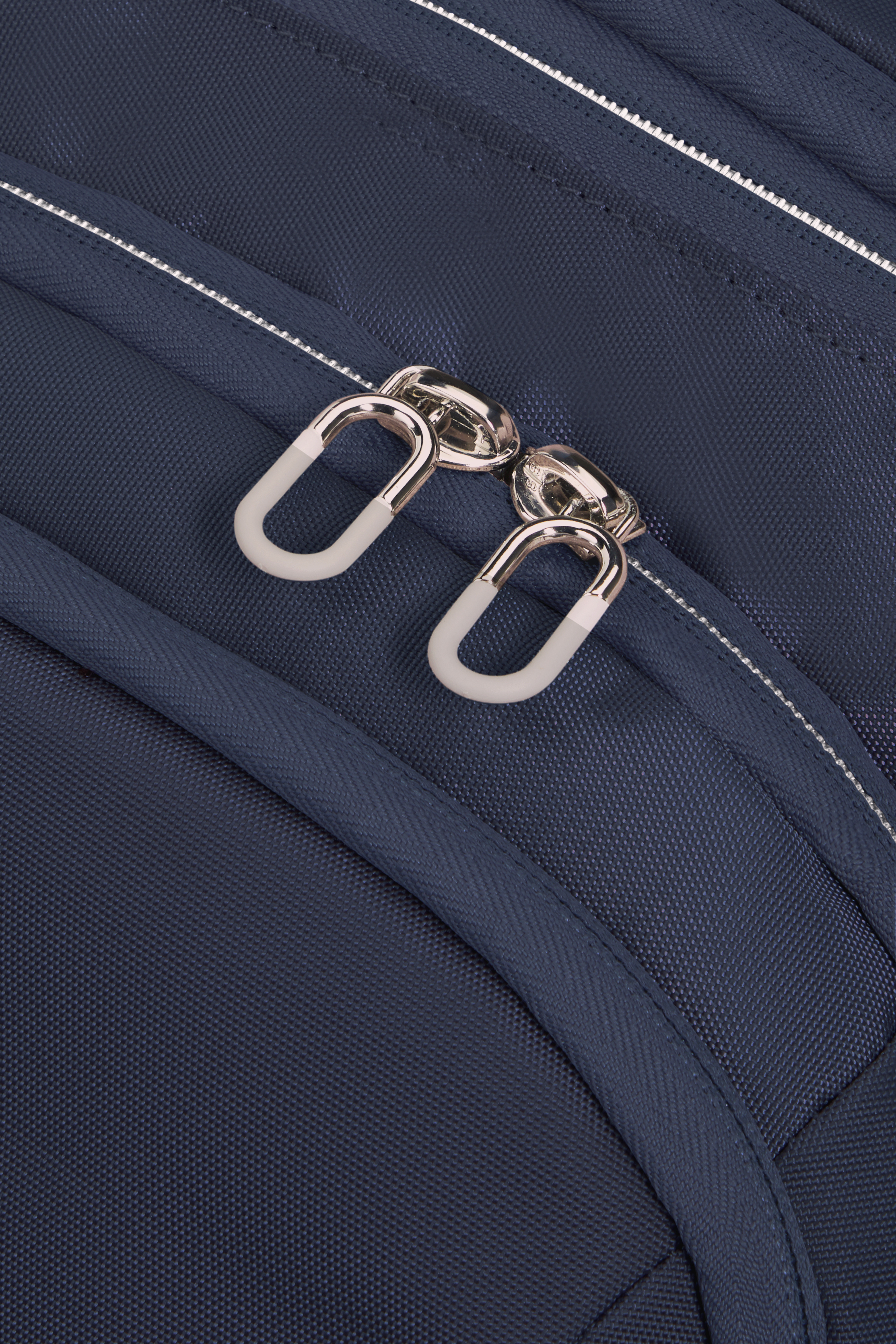 Nahaufnahme einer blauen Tasche mit silbernen Reißverschlüssen und weißen Zippern.