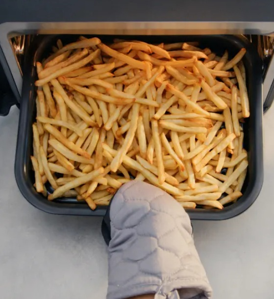 Taca pełna złotych frytek wyjmowana z frytkownicy beztłuszczowej.