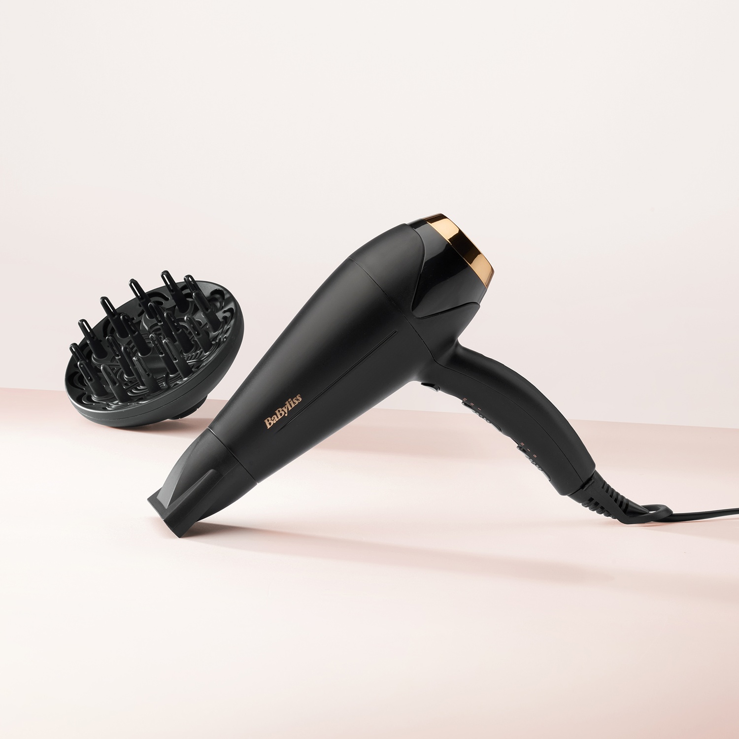 Asciugacapelli nero con diffusore, angolato su sfondo rosa.