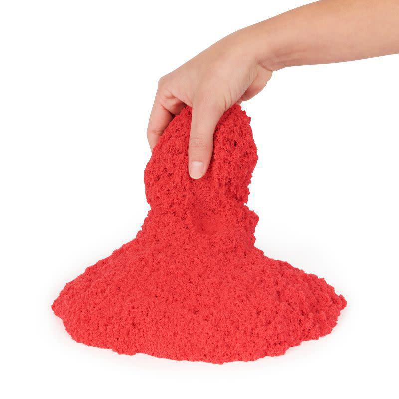 Hand hält roten Kinetiksand. Sand hat die Form eines Pilzes auf weißem Hintergrund.