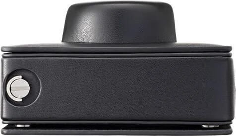 Czarne urządzenie z zaokrągloną górą, widok z boku, szczegóły przycisku i podstawy.