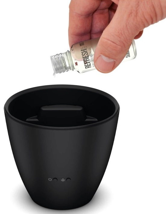 Ręka wlewa płyn z małej butelki do czarnego dyfuzora. Na butelce napis Refresh.