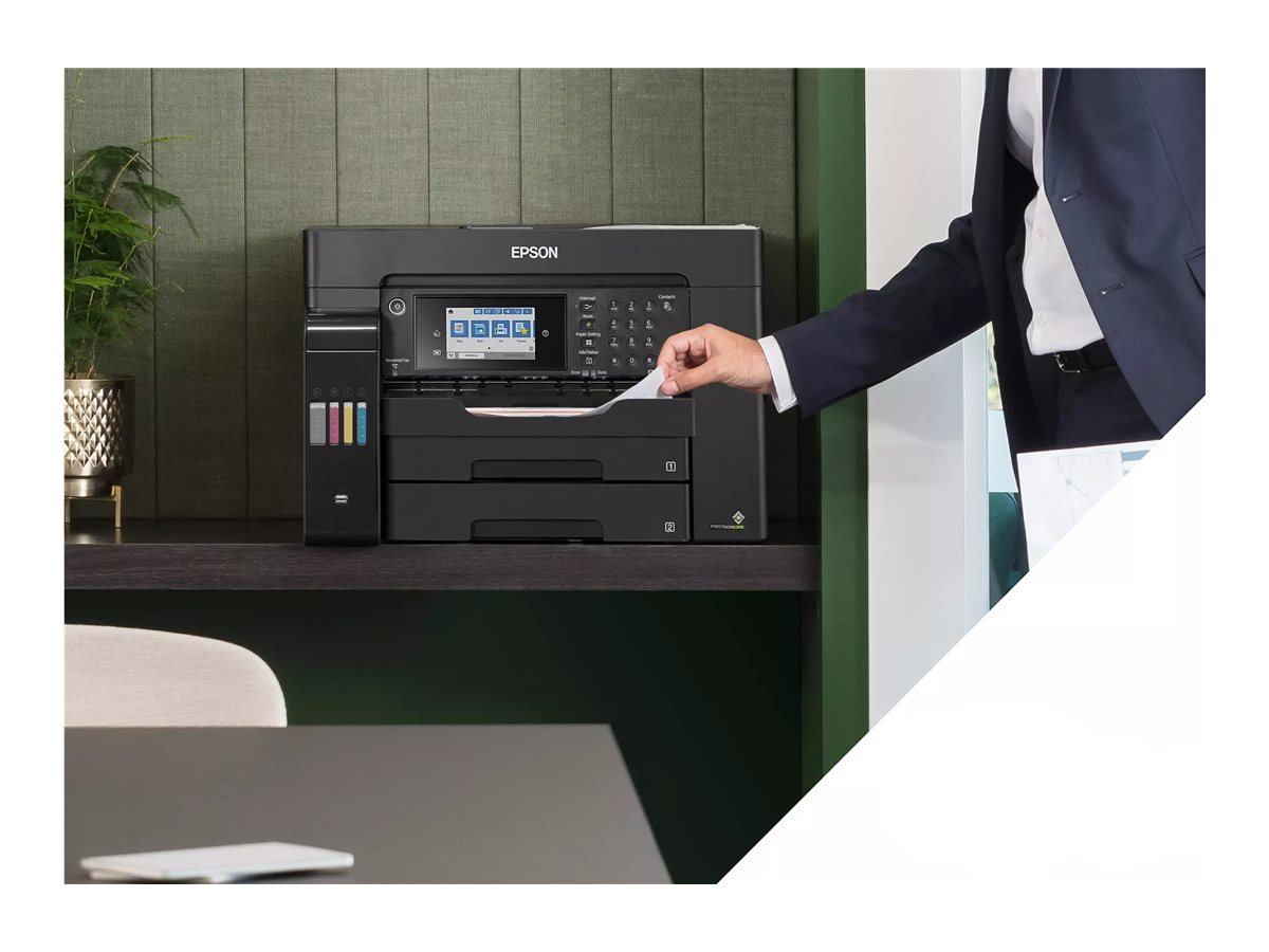 Person legt Papier in einen schwarzen Epson-Drucker auf einem Regal. Grüne Wand und Schreibtisch sichtbar.
