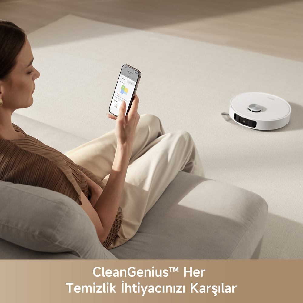 Bir kadın, robot süpürgeyi kontrol etmek için telefon kullanıyor.