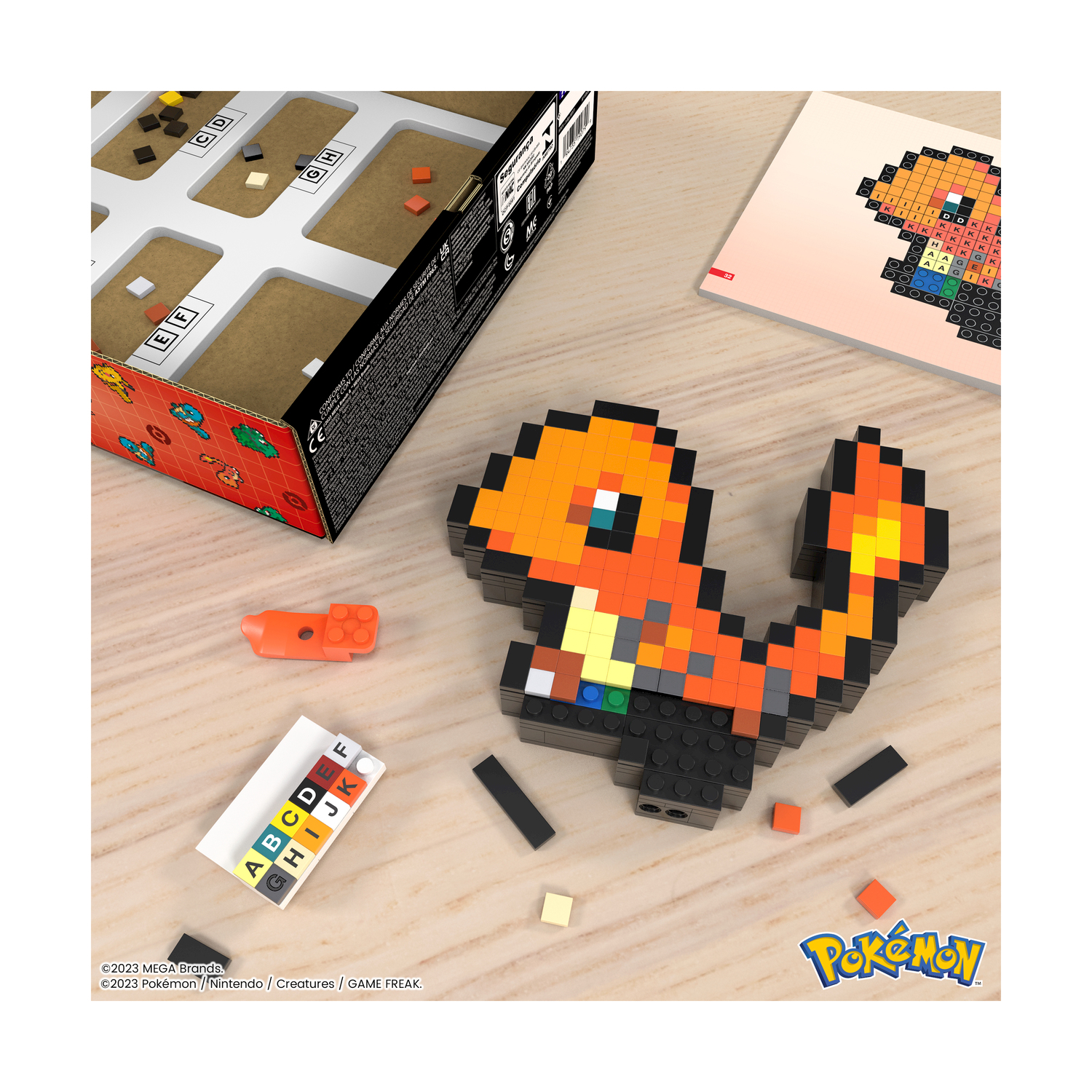 Giocattolo Charmander pixelato vicino a blocchi e istruzioni su un tavolo.
