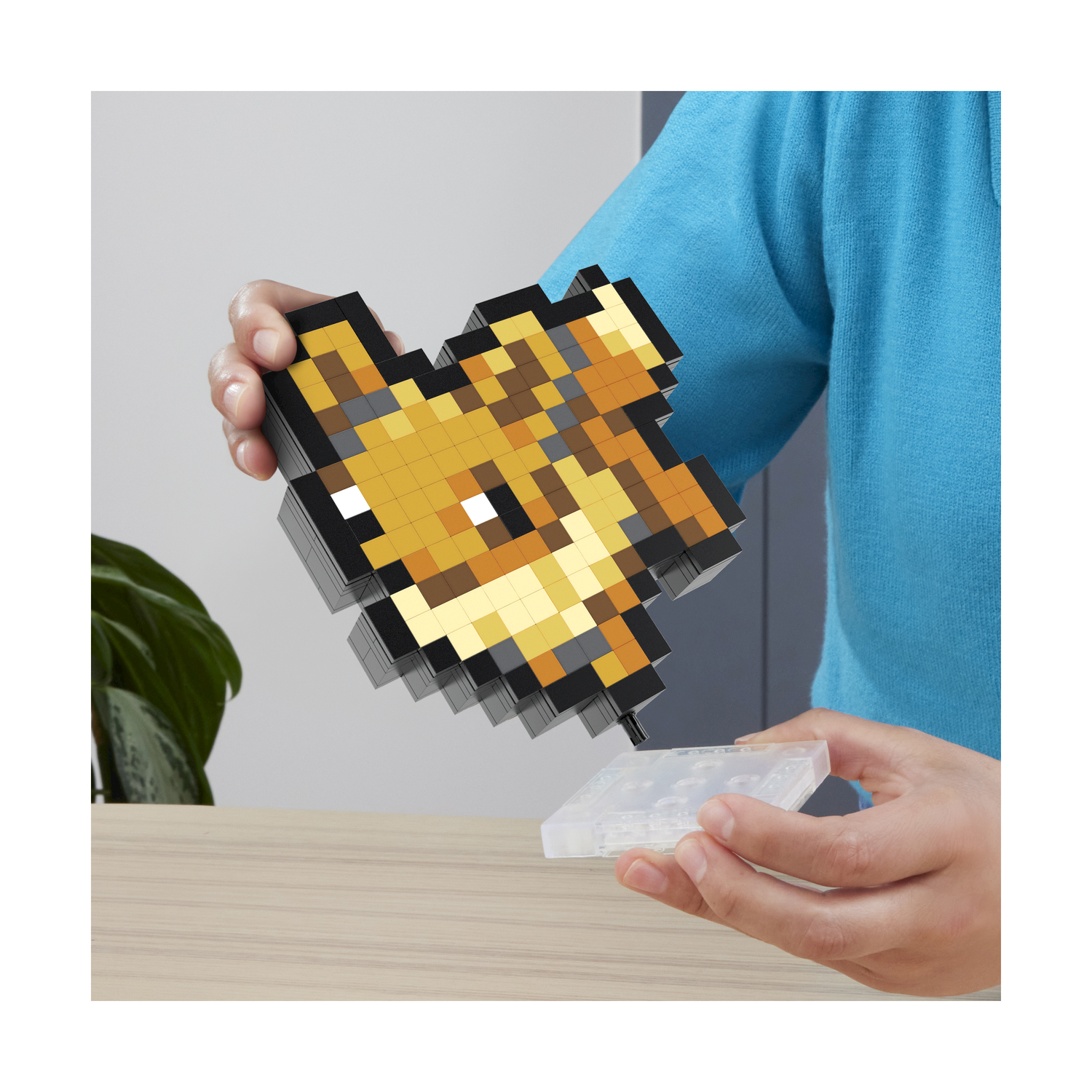 Una persona tiene in mano un giocattolo pixelato a forma di volpe.