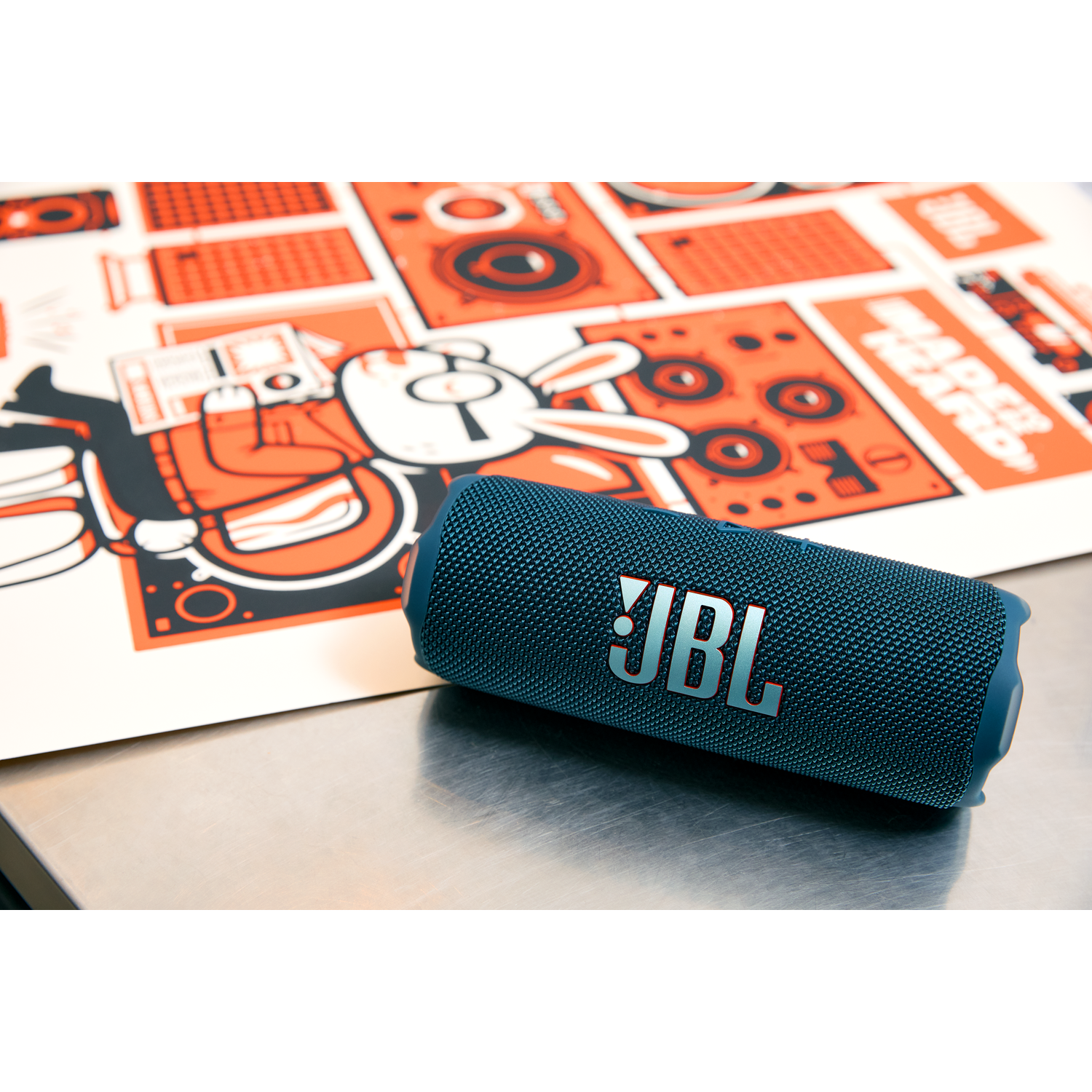 Enceinte JBL bleue sur surface métallique, fond graphique.