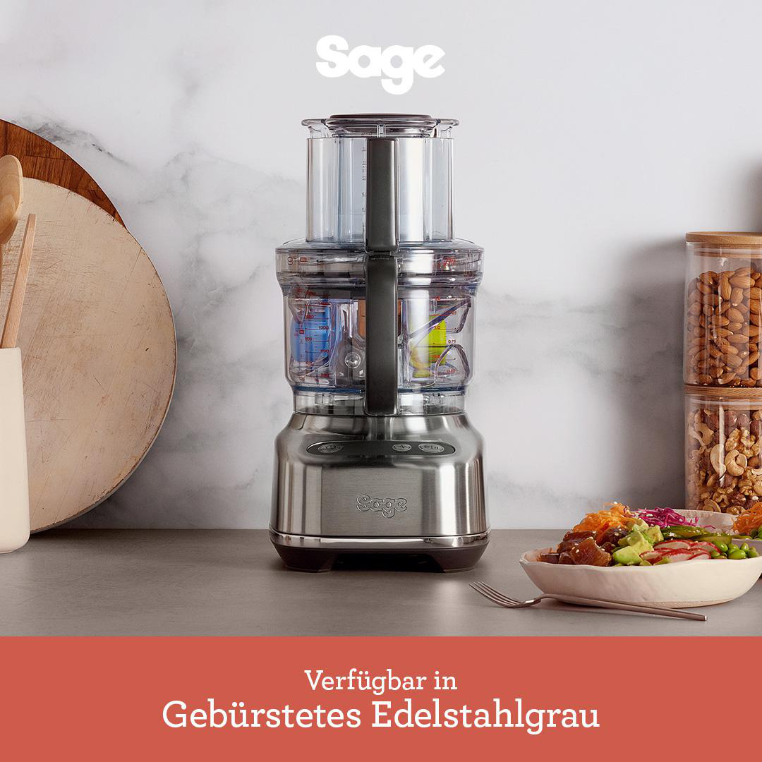 Ein Küchenmaschine aus Edelstahl mit einer Salatschüssel auf der Theke.