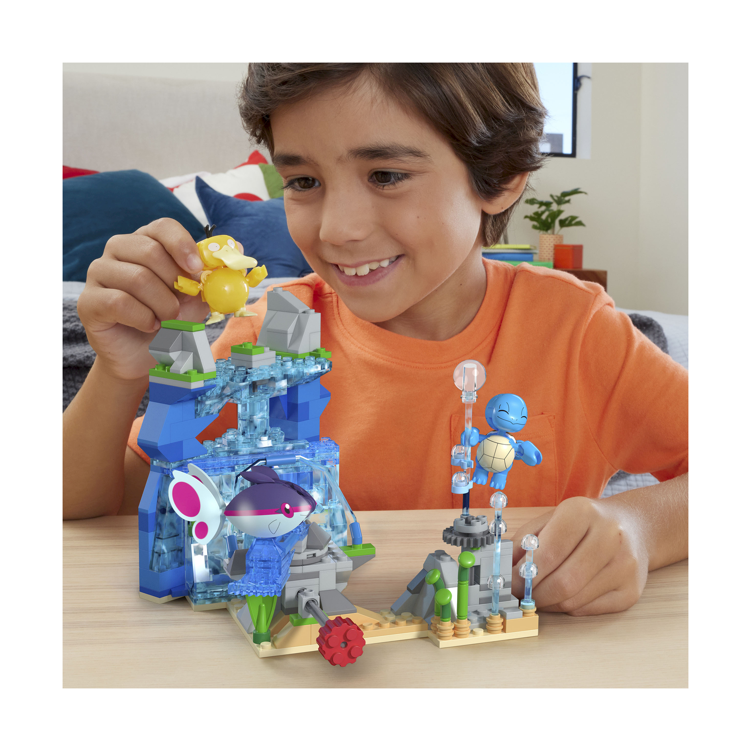 Un ragazzo gioca con Lego Pokémon. Un edificio con cascata e personaggi.