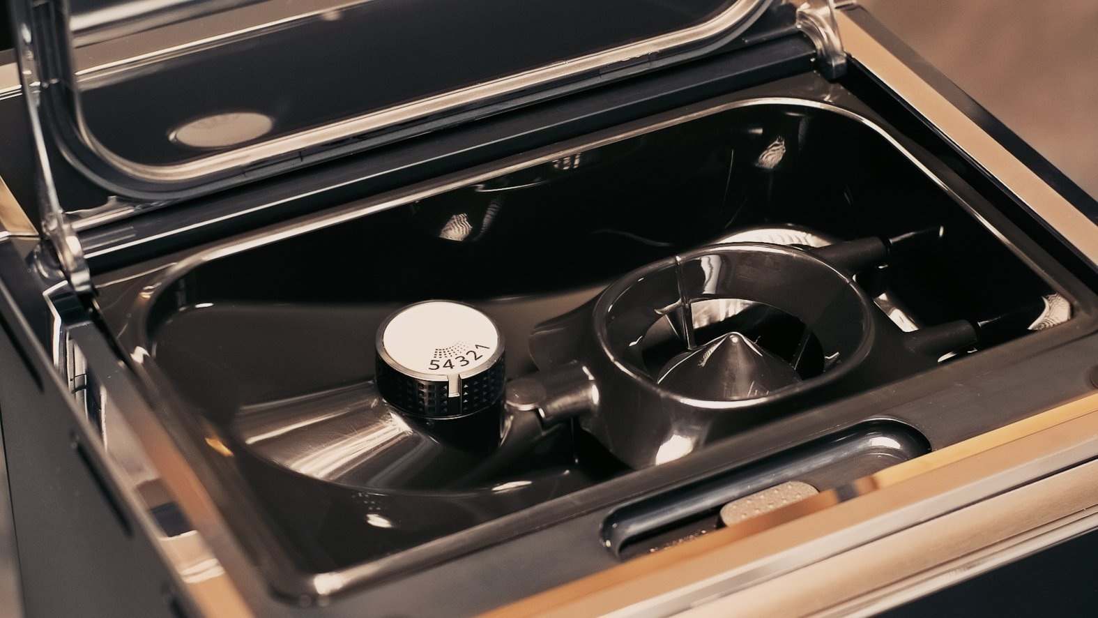 Wnętrze urządzenia kuchennego z pokrętłem i metalowymi elementami.