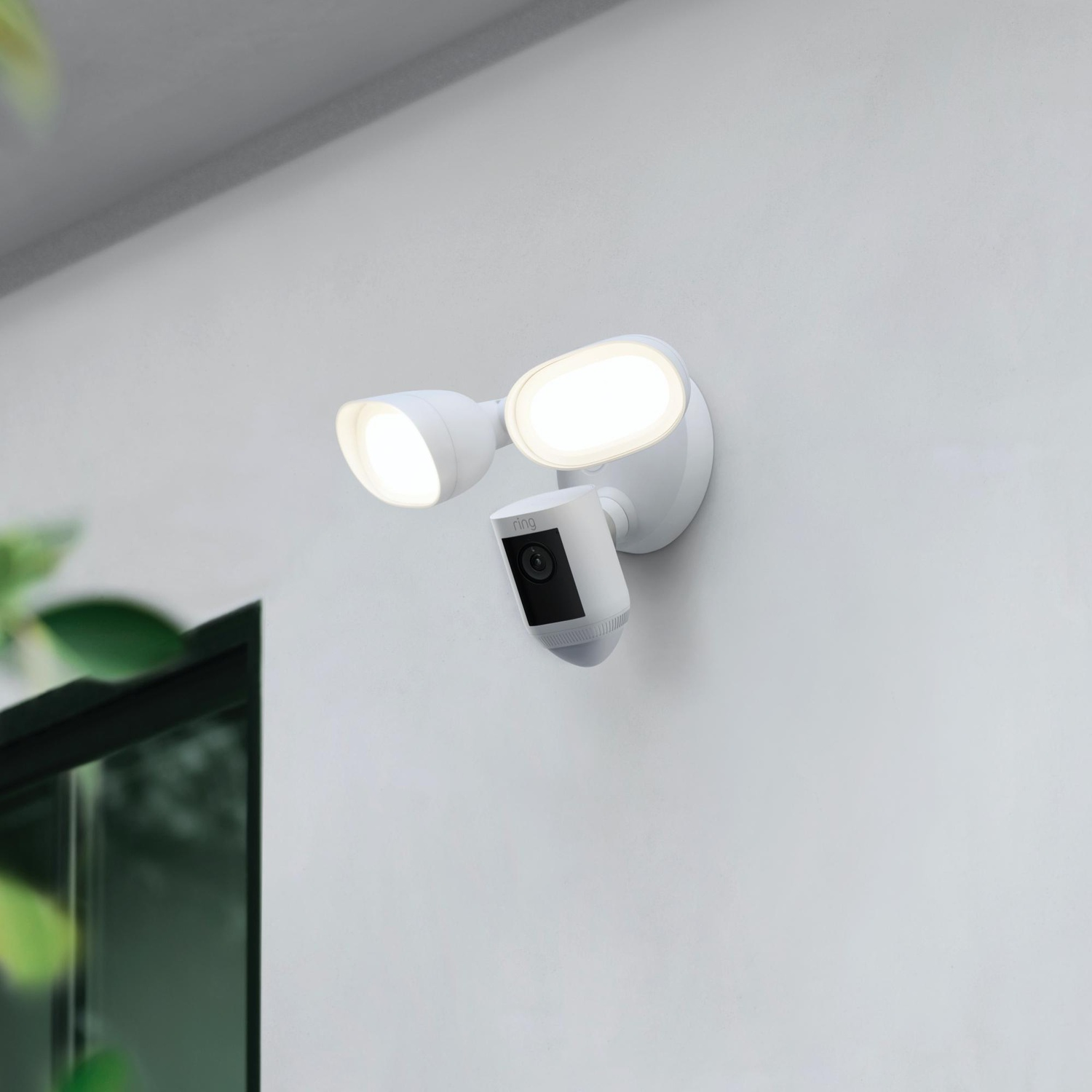 Witte aan de muur gemonteerde veiligheidslamp met camera. Twee lampen en een camera eronder.