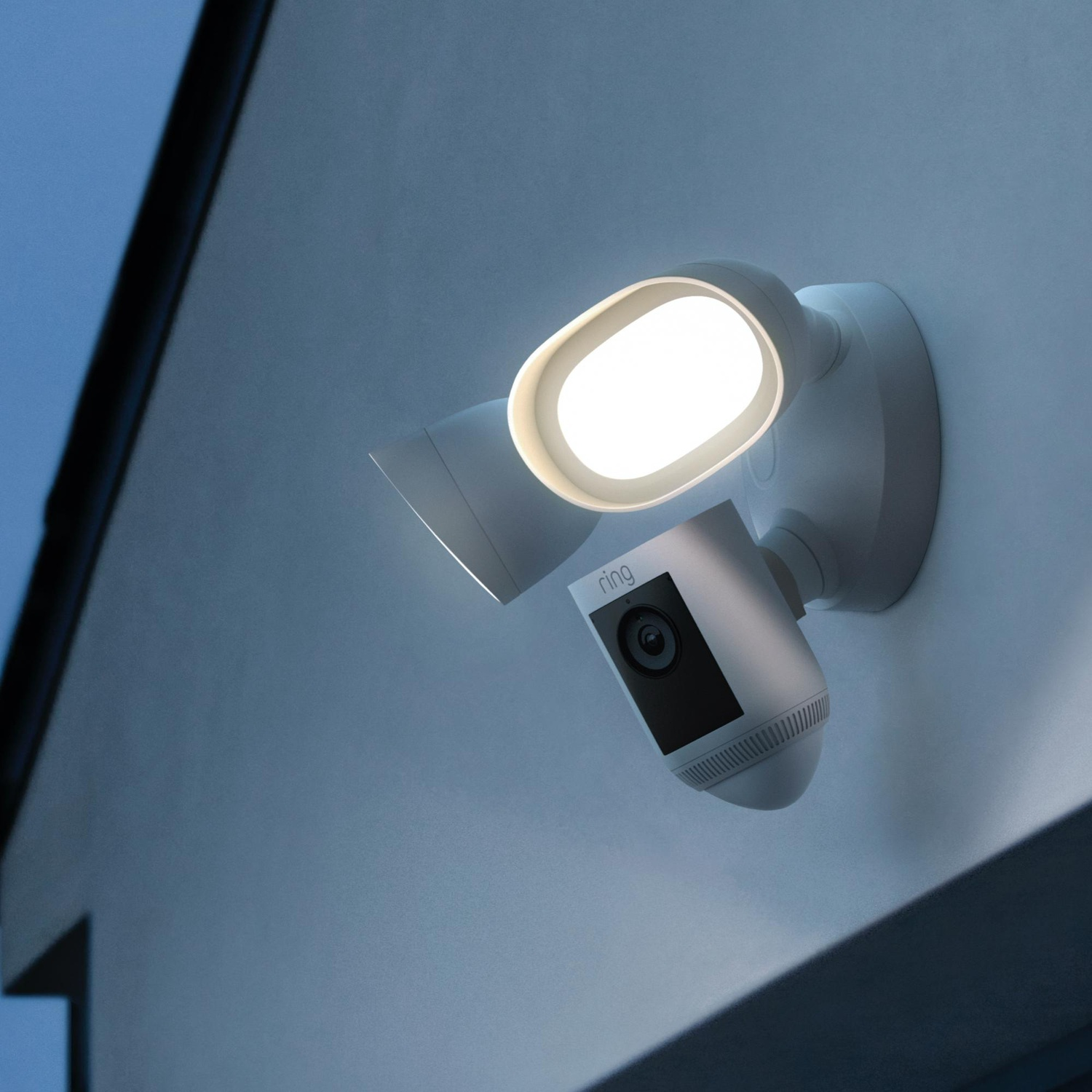 Ring buitenlamp en camera gemonteerd op een muur, 's nachts verlicht, blauwe lucht op de achtergrond.