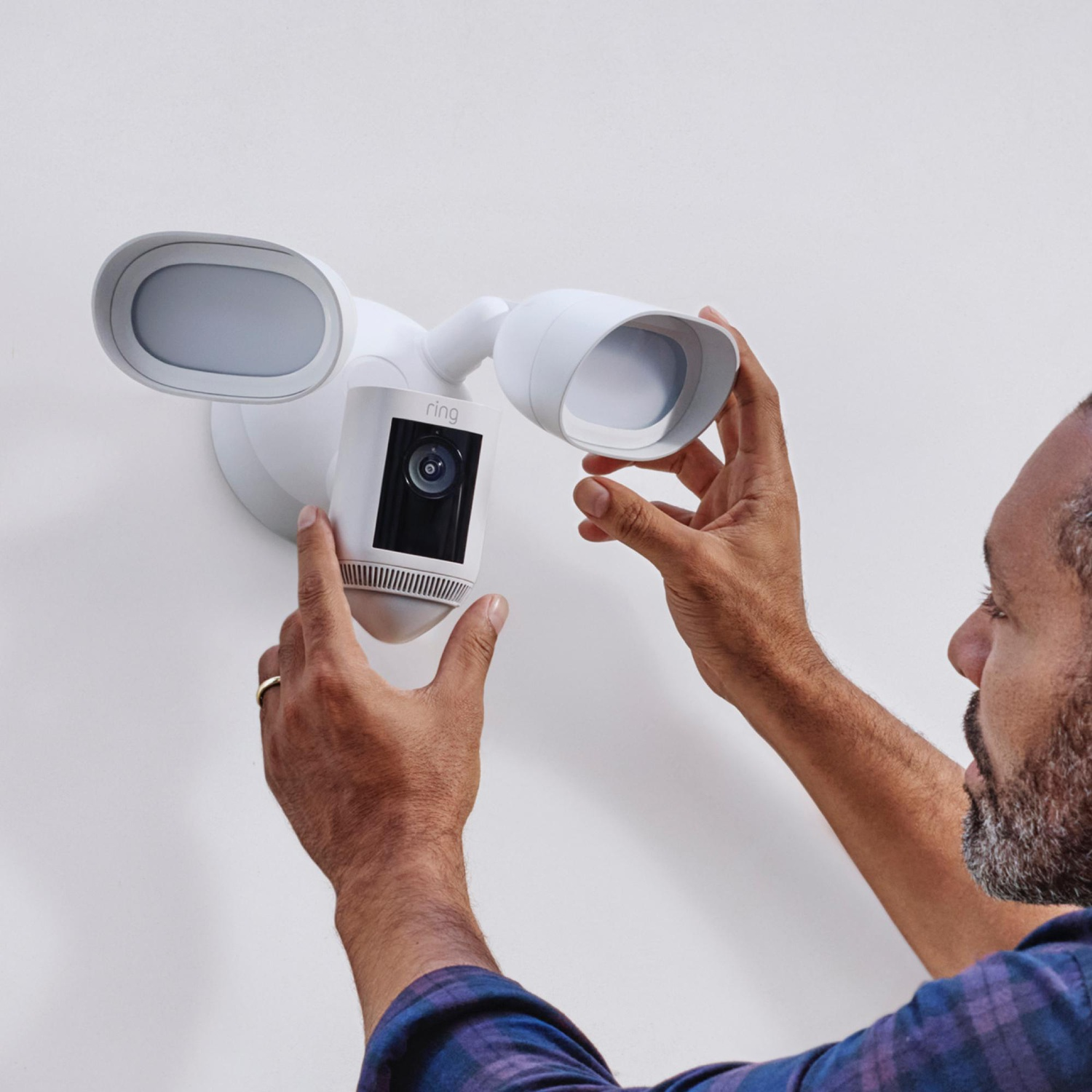 Man installeert een Ring veiligheidslamp. Witte muur achtergrond.