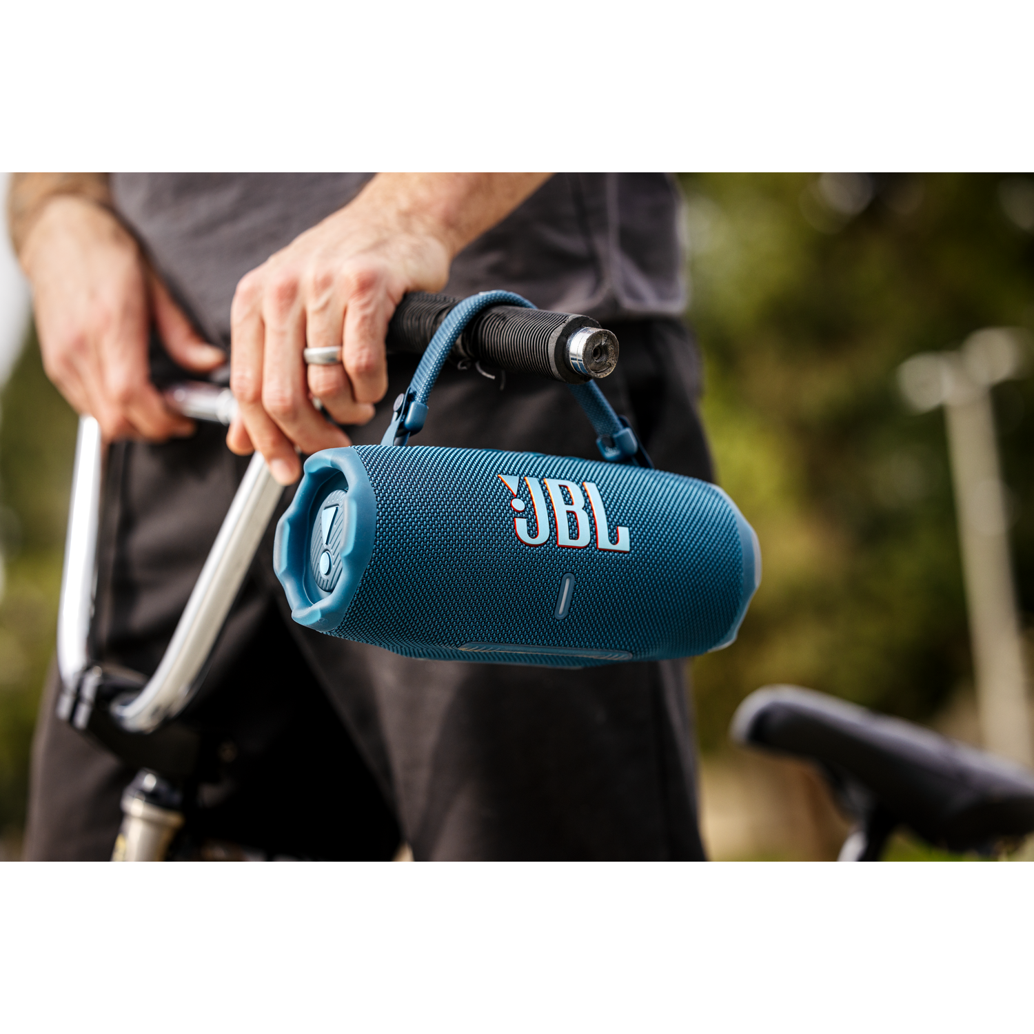 Mann hält JBL-Lautsprecher an Fahrradlenker befestigt.