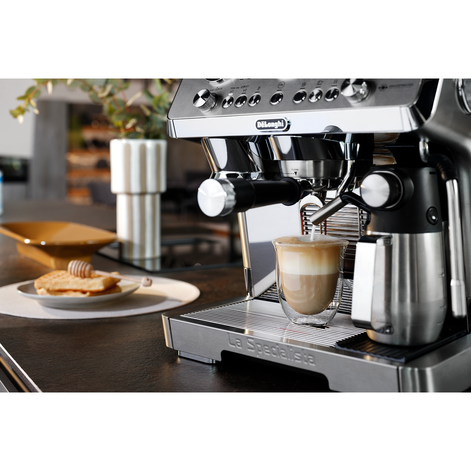 An espresso machine making coffee with a glass of latte.
