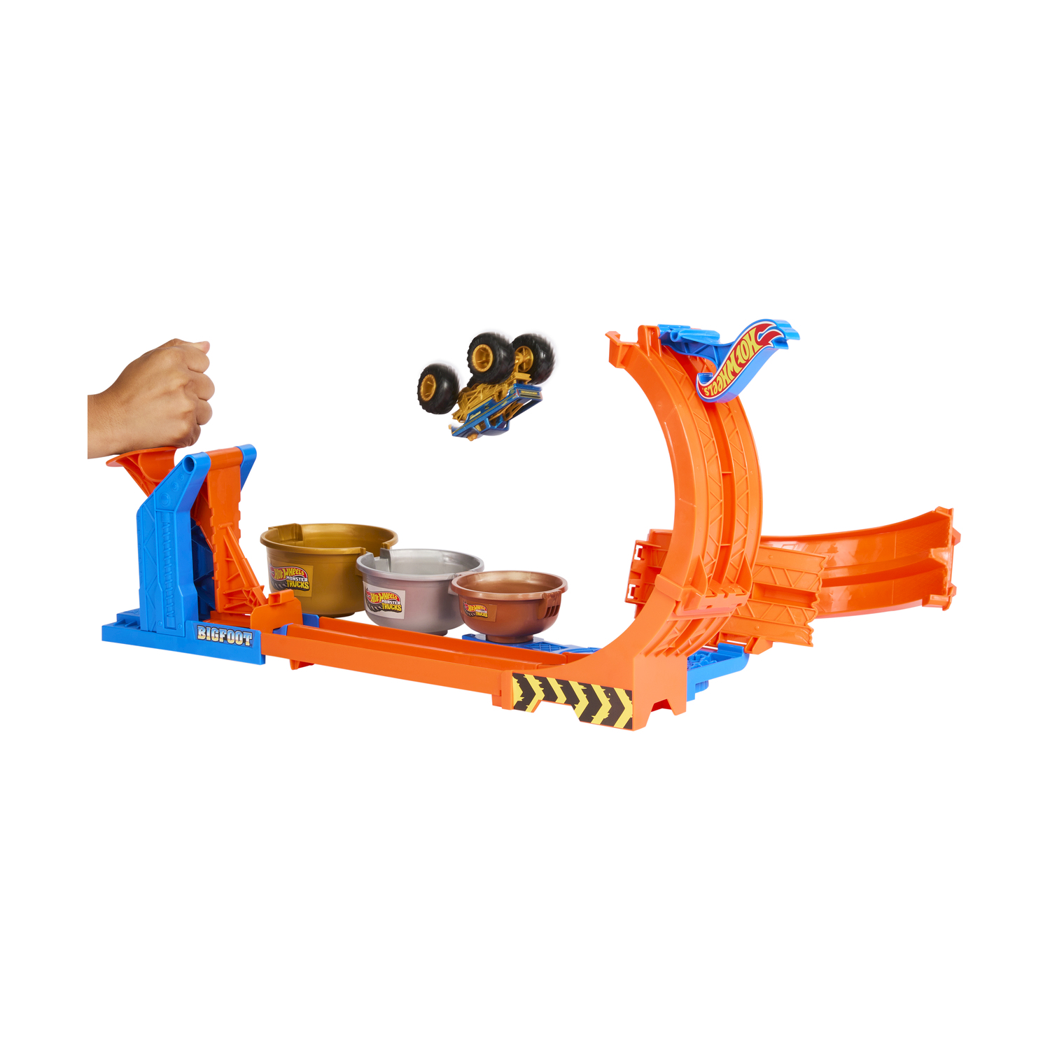 Una pista di auto Hot Wheels con un monster truck che si lancia attraverso un anello, sopra i contenitori.