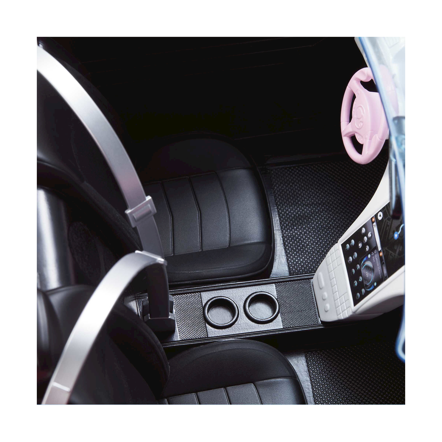 Interno di un'auto giocattolo, sedili neri, volante rosa e cruscotto bianco.