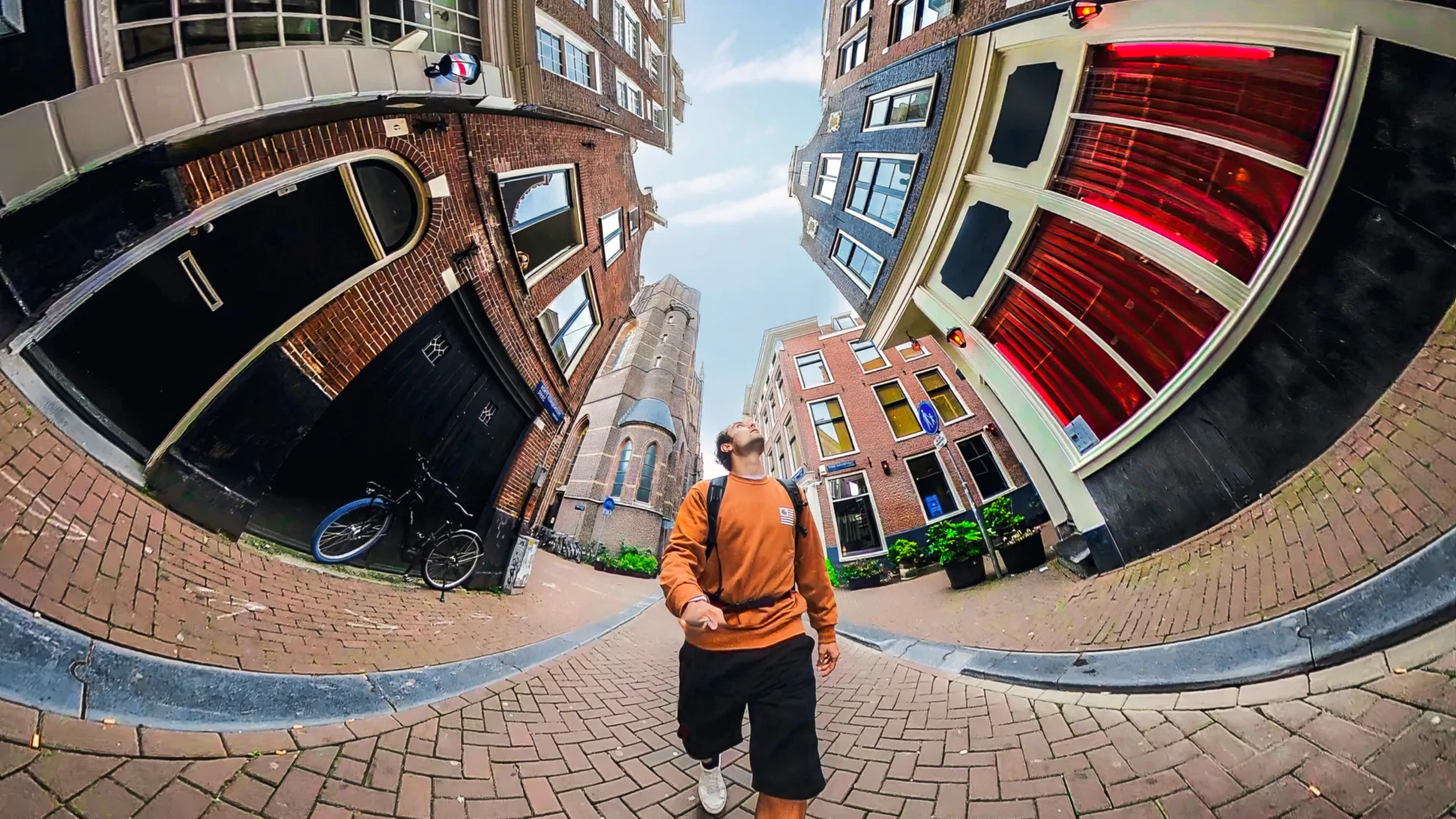 Scatto grandangolare di una strada ad Amsterdam. Edifici su entrambi i lati, persona che cammina al centro.