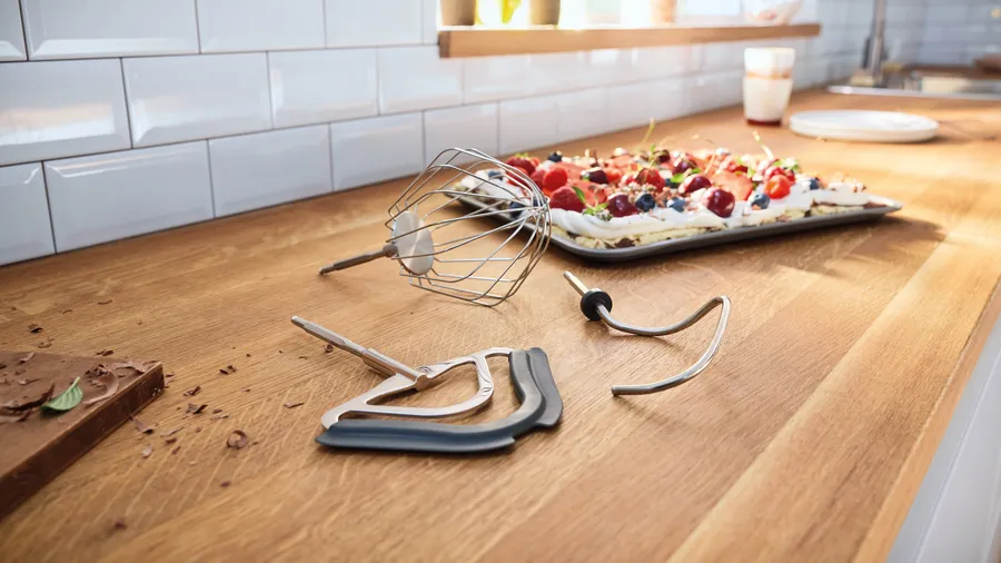 Ustensiles de pâtisserie sur un comptoir en bois, incluant un fouet et des accessoires.