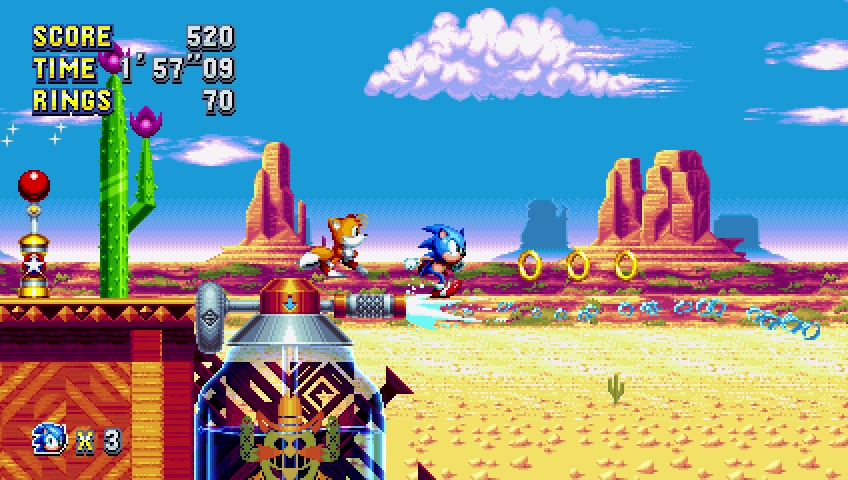 Sonic e Tails corrono in un ambiente desertico. Anelli e un cactus sono visibili.