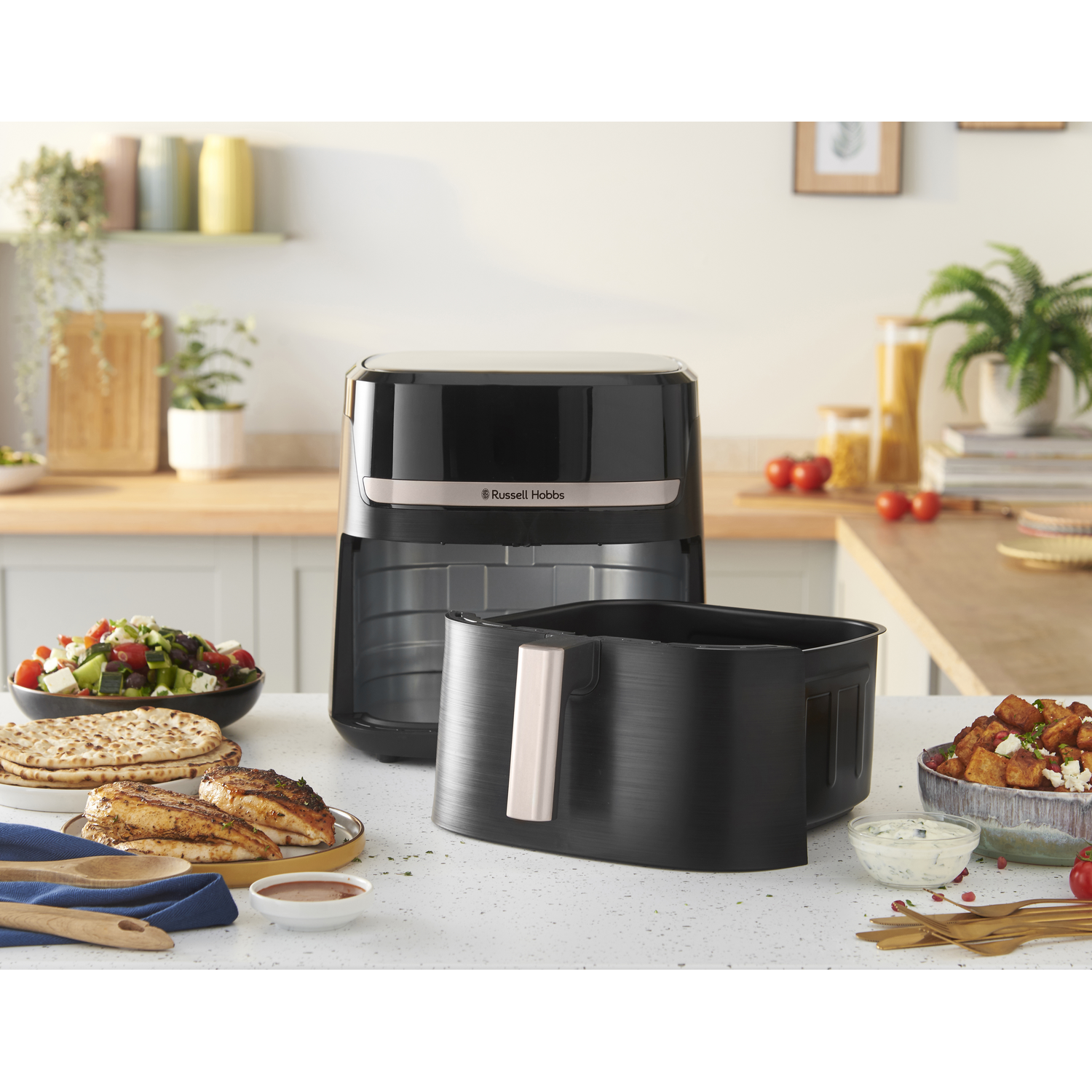 Een airfryer met eten op het aanrecht.