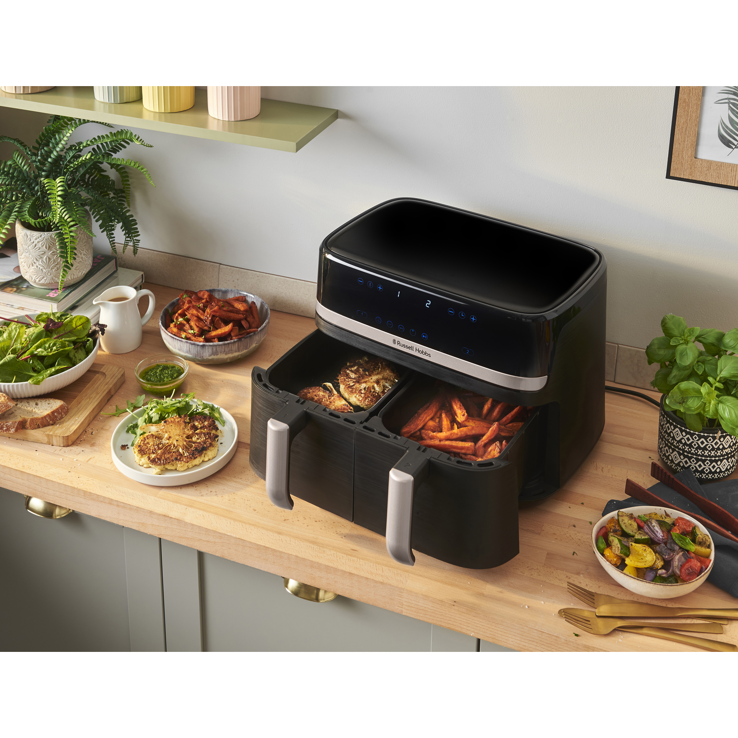 A black and silver air fryer with food inside and on the counter.