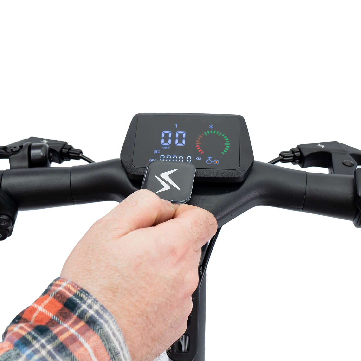 Una persona sosteniendo un mando a distancia para un salpicadero digital negro de scooter. Muestra velocidad y otros datos.