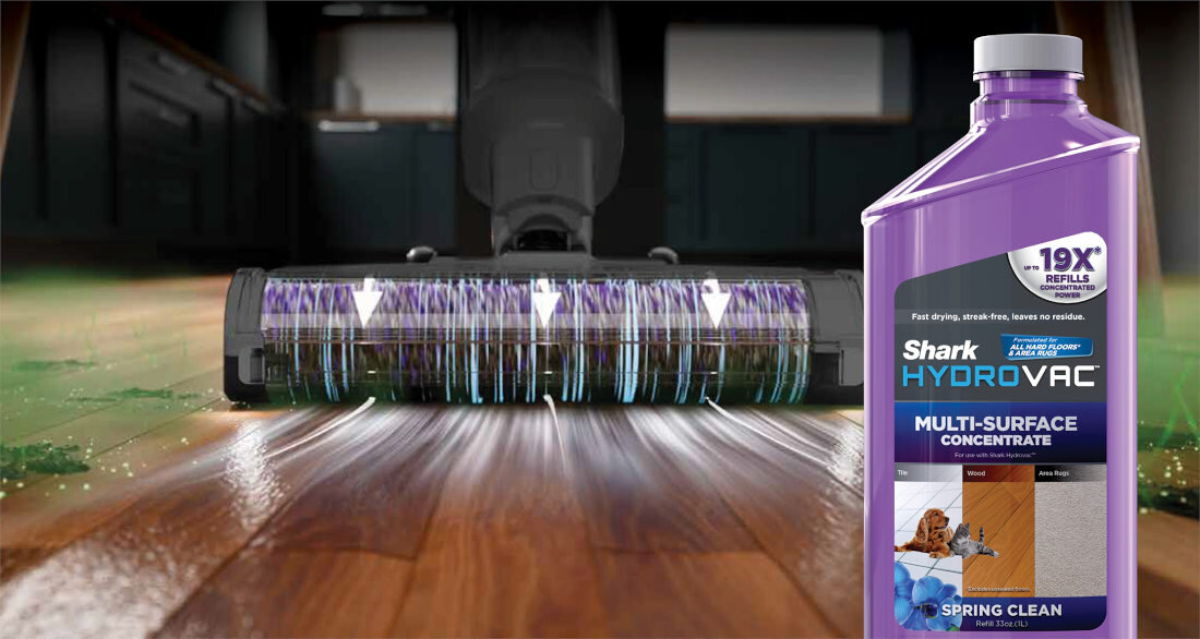 Odkurzacz z fioletową butelką z płynem na drewnianej podłodze. Odkurzacz jest w użyciu, z białymi strzałkami.