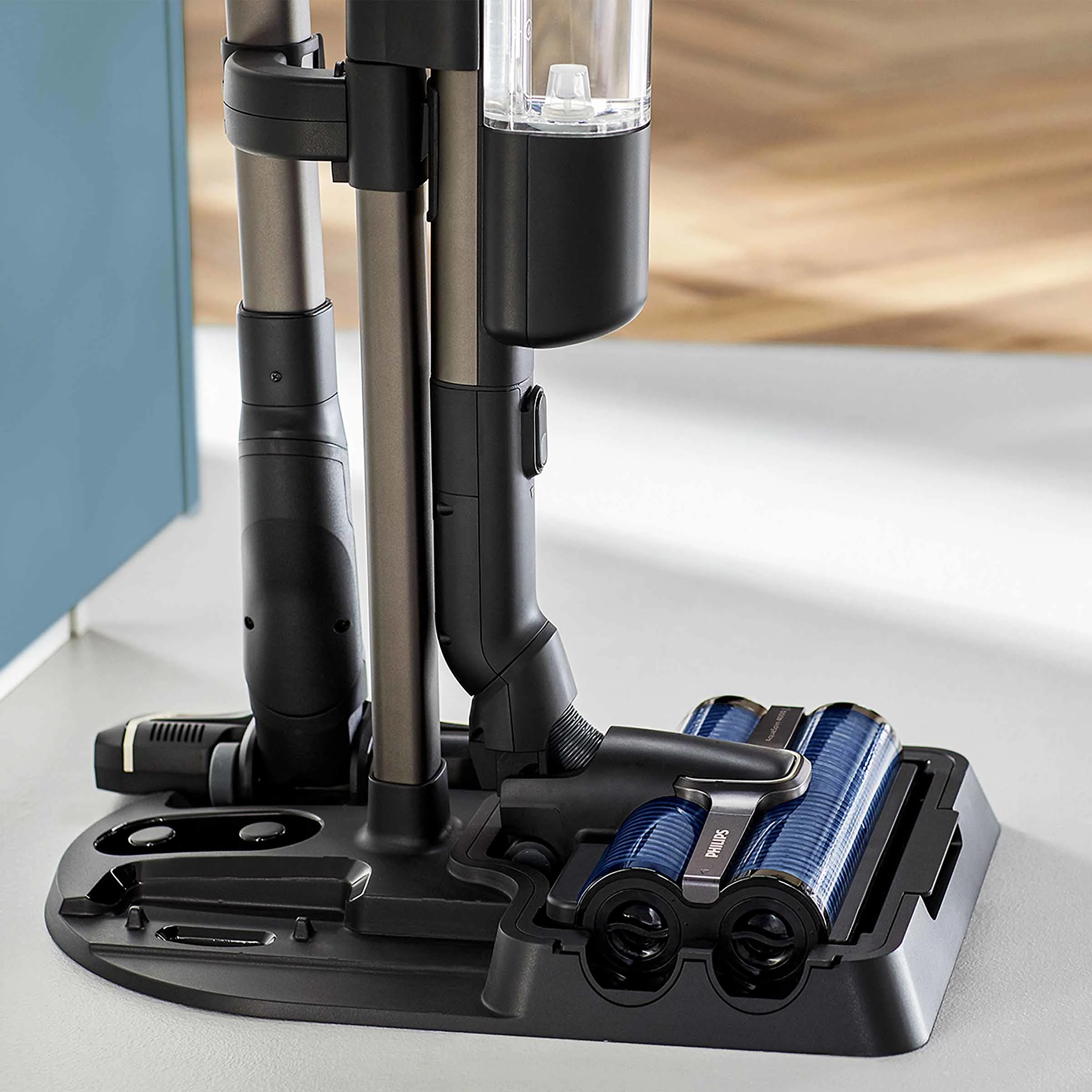 Podstawa odkurzacza z dwoma niebieskimi rolkami i stacją ładującą.