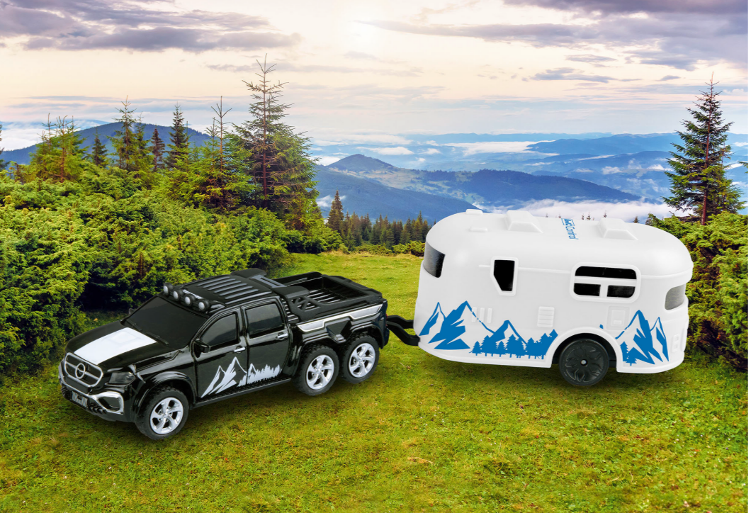 Ein schwarzer LKW mit weißem Wohnwagen in einer Berglandschaft mit grünen Bäumen.
